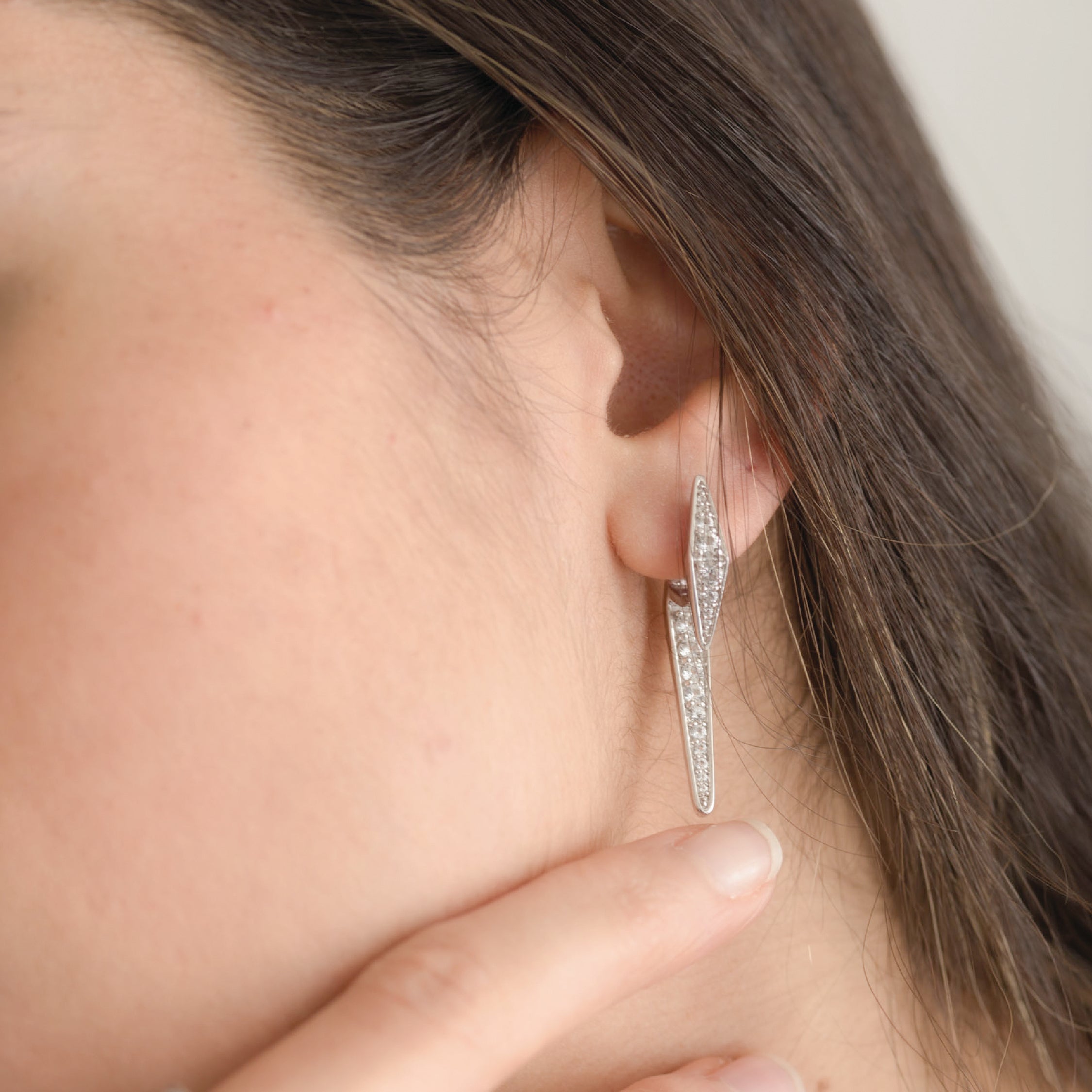 Close-up of 14K solid gold diamond earrings with sleek design on ear.
