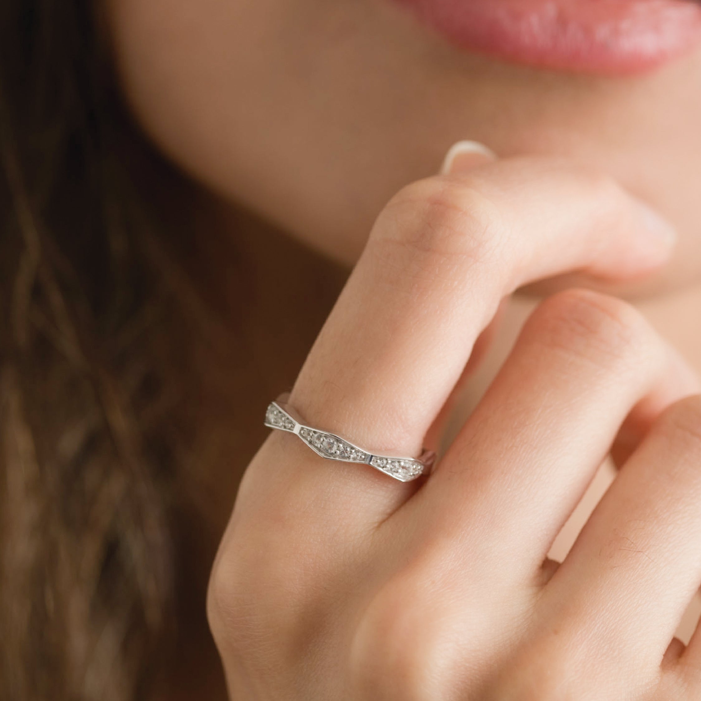 14K gold ring with lab-grown diamonds on a woman's finger, elegant and shiny.