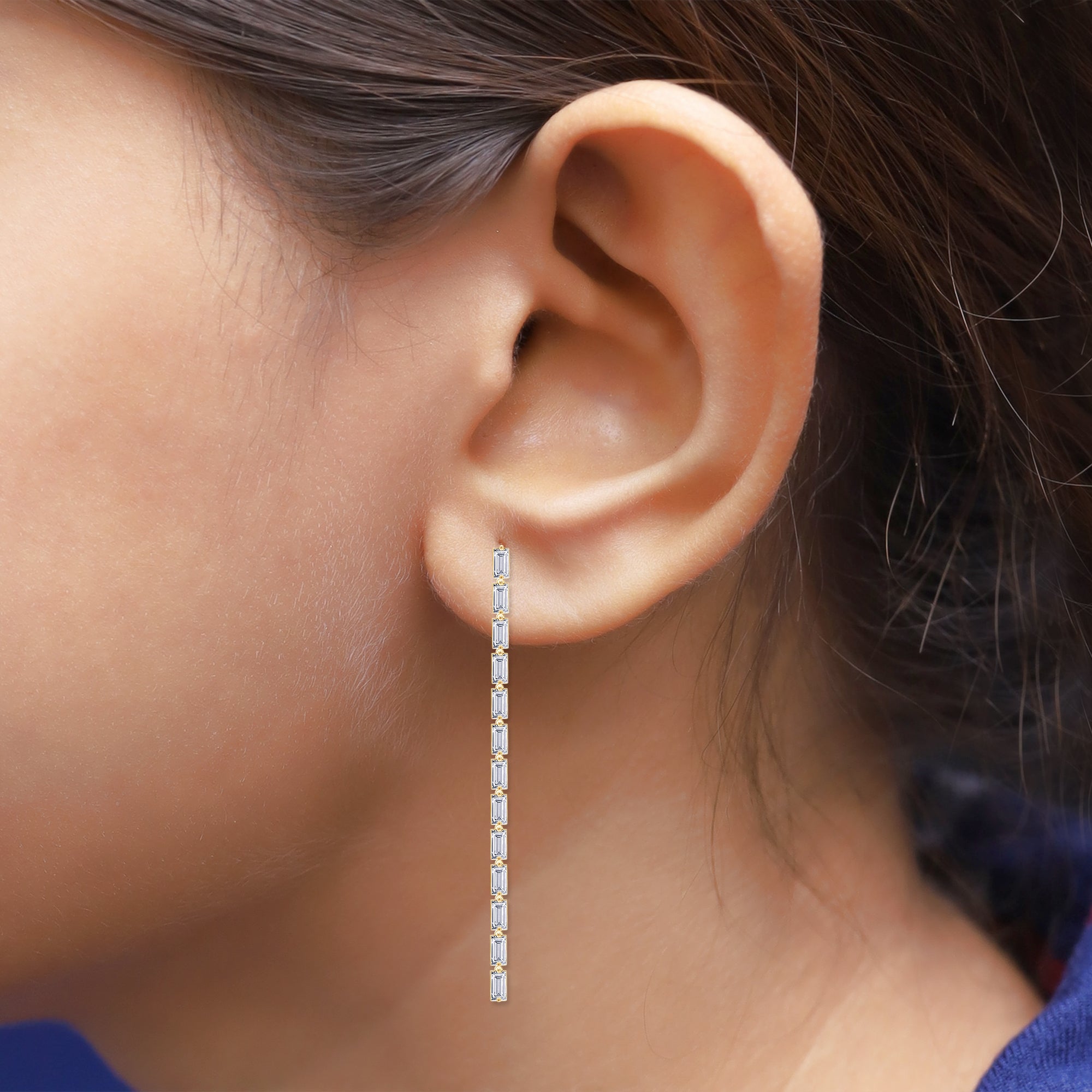 Close-up of an ear wearing a diamond earring with a blurred background