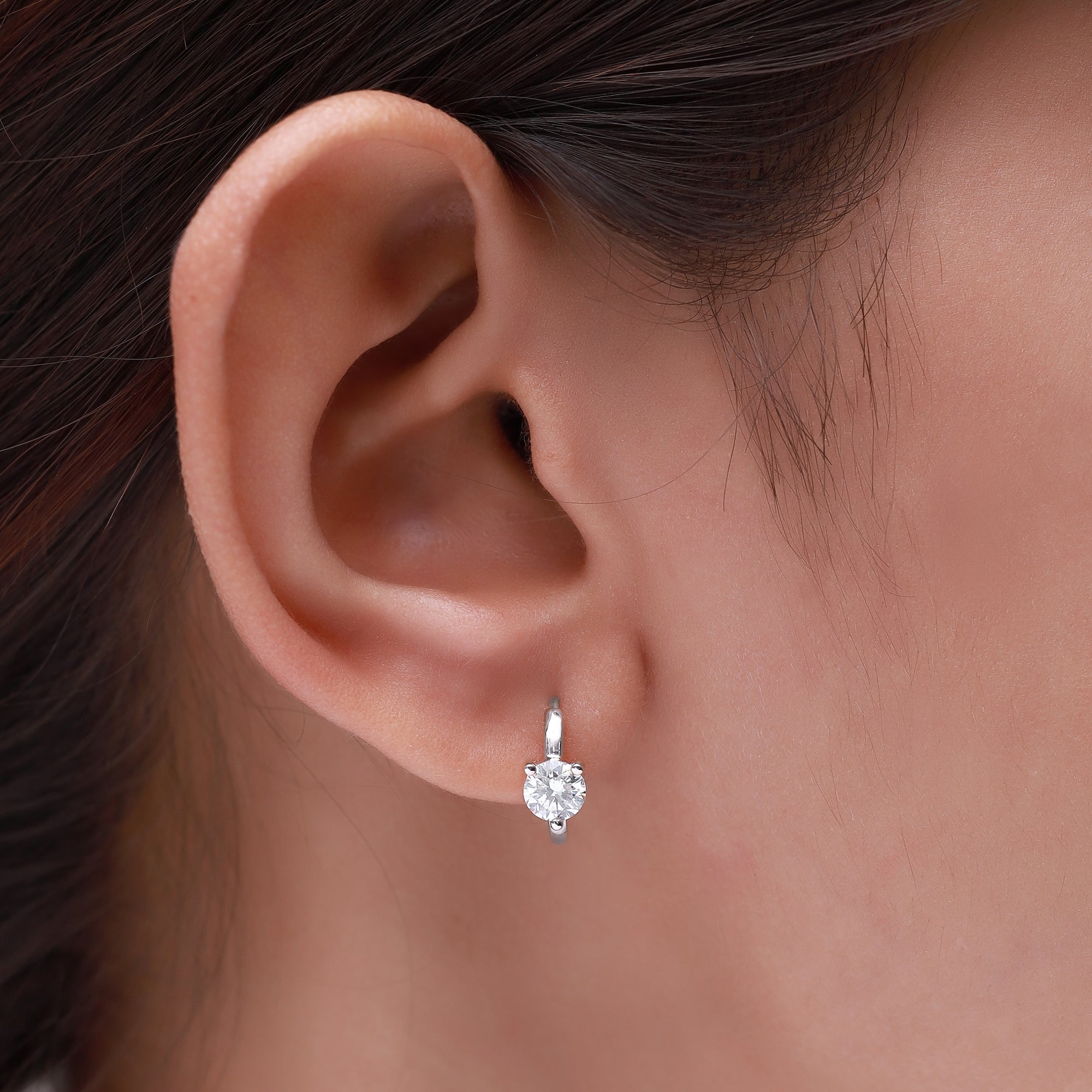 Close-up of an ear wearing a diamond earring with a blurred background