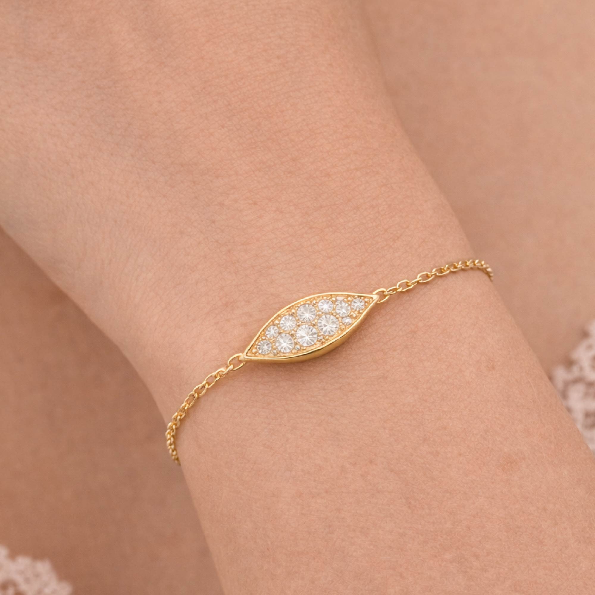Gold bracelet with diamond accents on a wrist against a neutral background