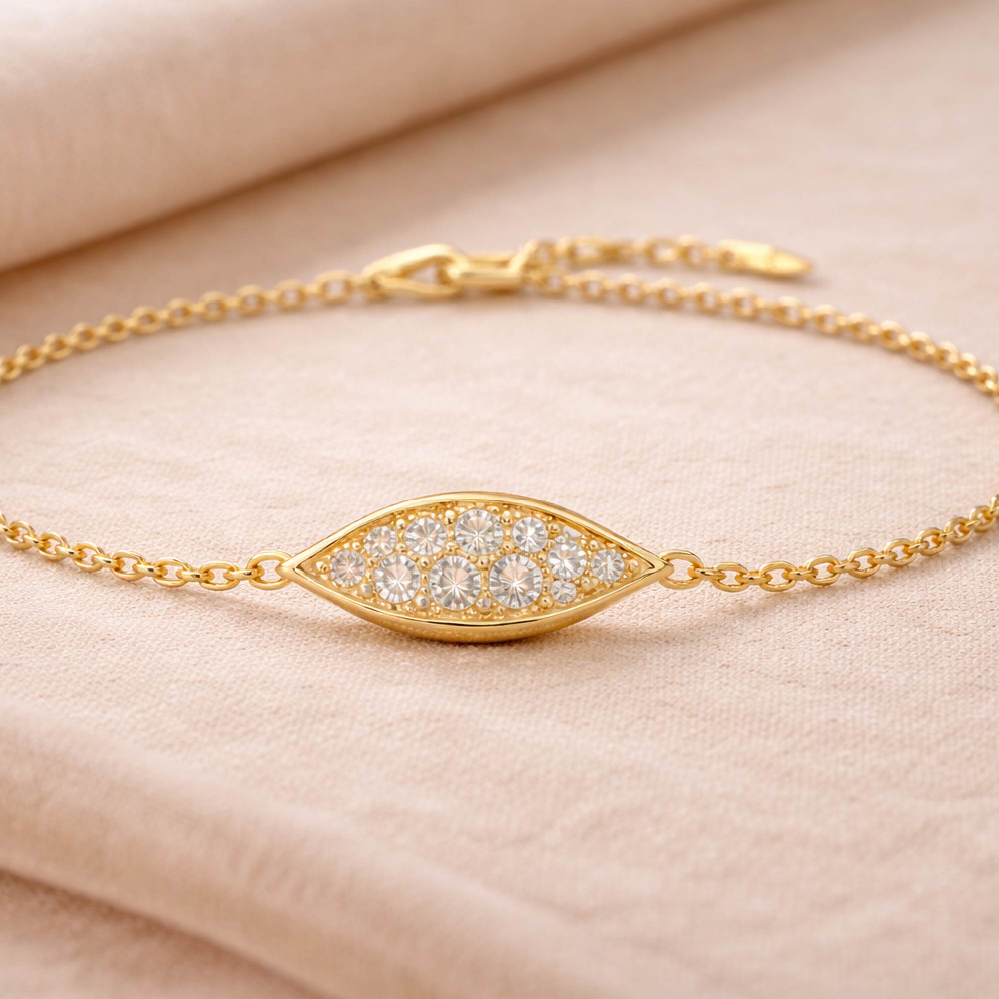Gold bracelet with diamond eye design on a beige background