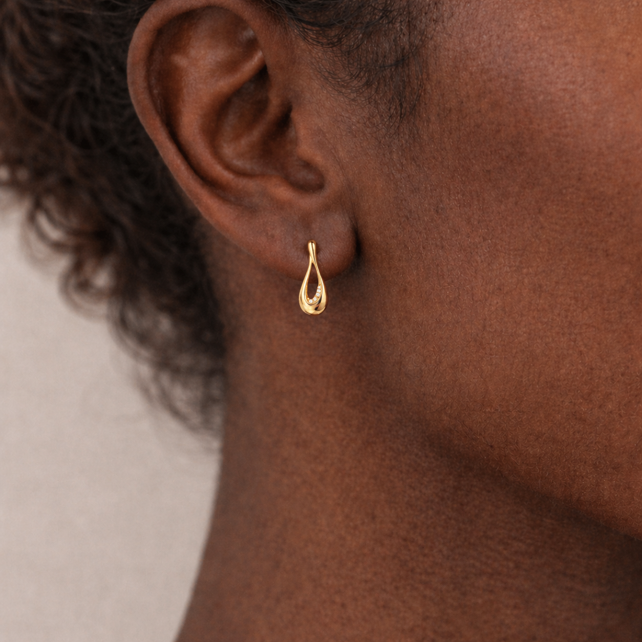 Gold earring worn by a person with a neutral background