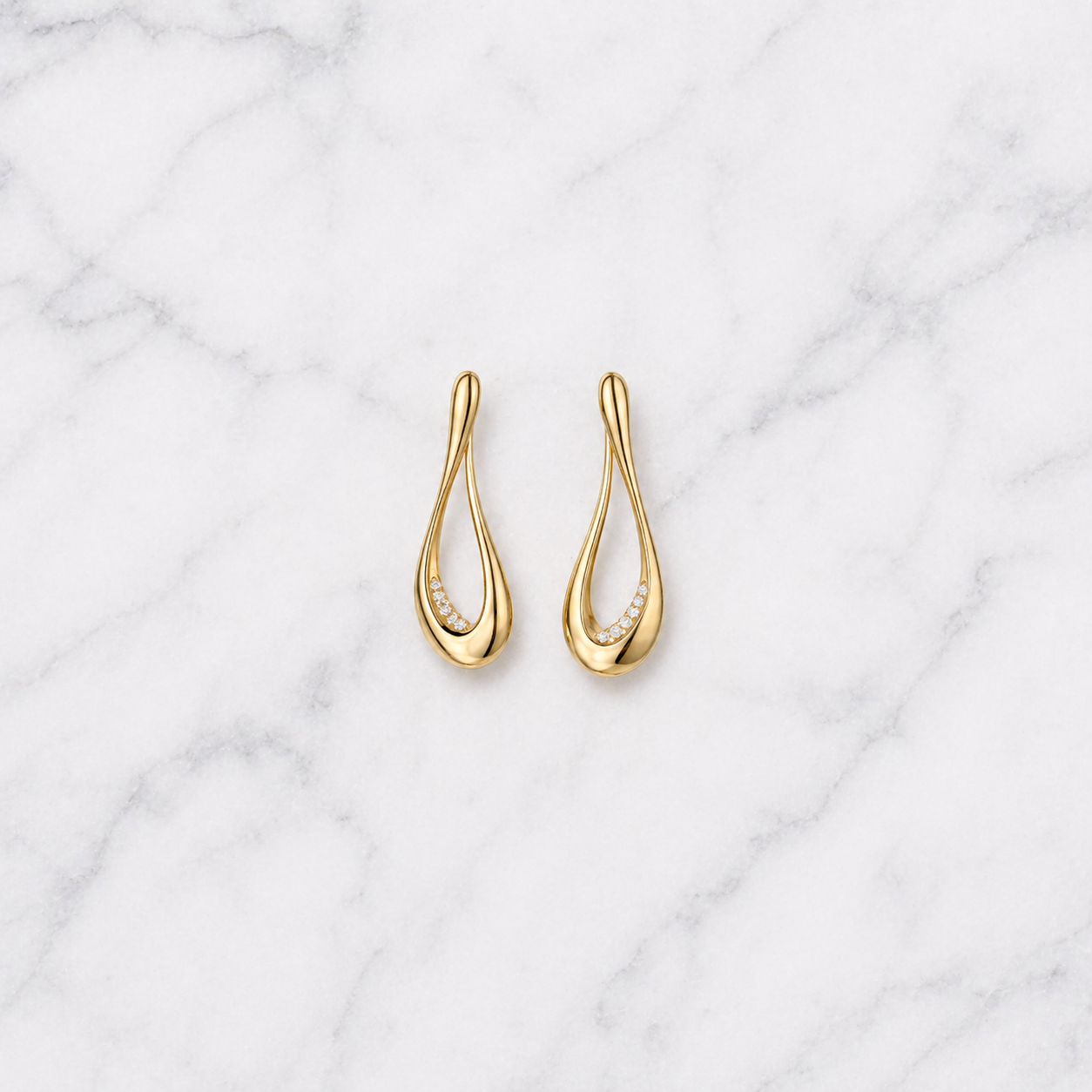 Gold earrings with diamond accents on a marble background