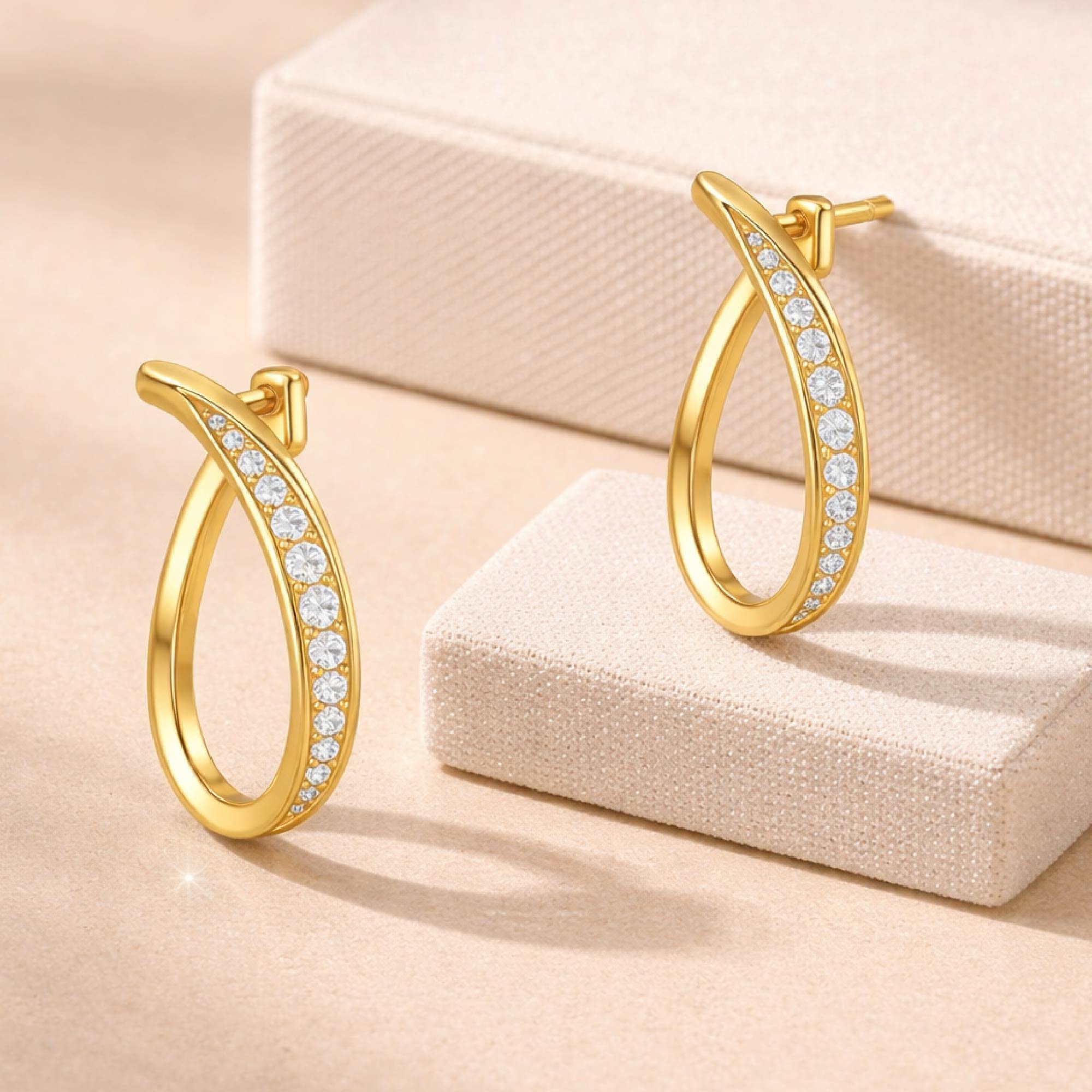 Gold hoop earrings with gemstones on a beige surface
