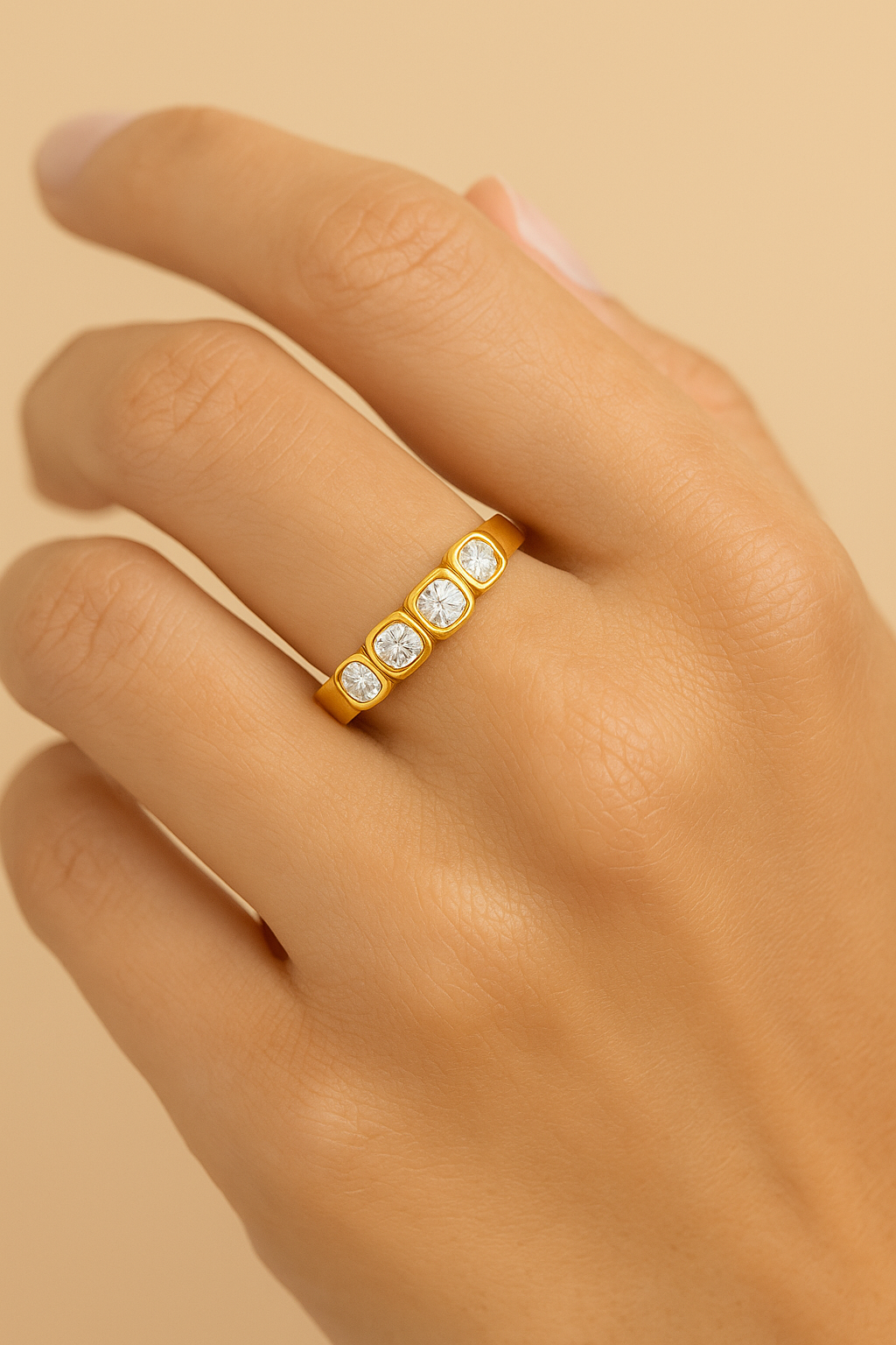 Gold ring with diamonds on a hand against a beige background