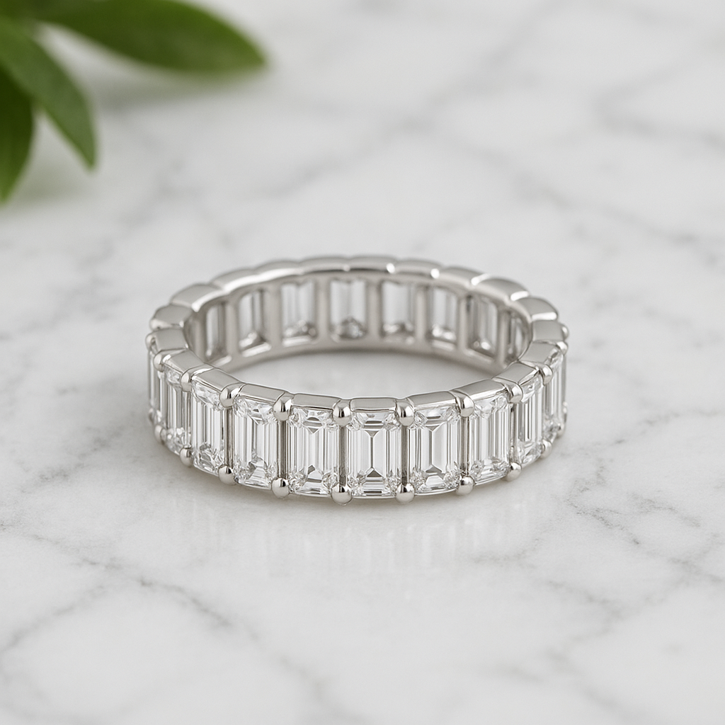 Silver ring with emerald-cut gemstones on a marble surface