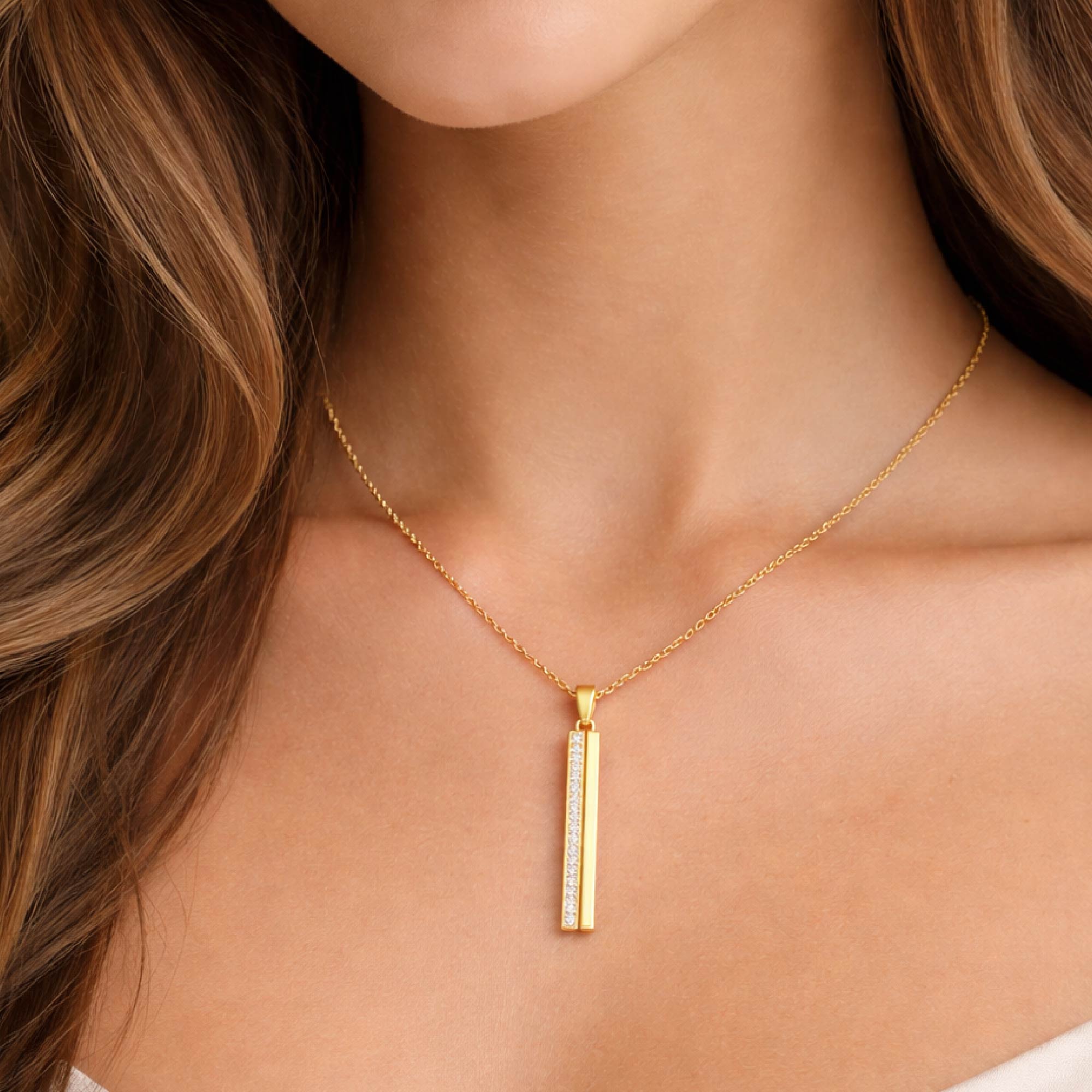 Gold necklace with a pendant on a person with wavy hair