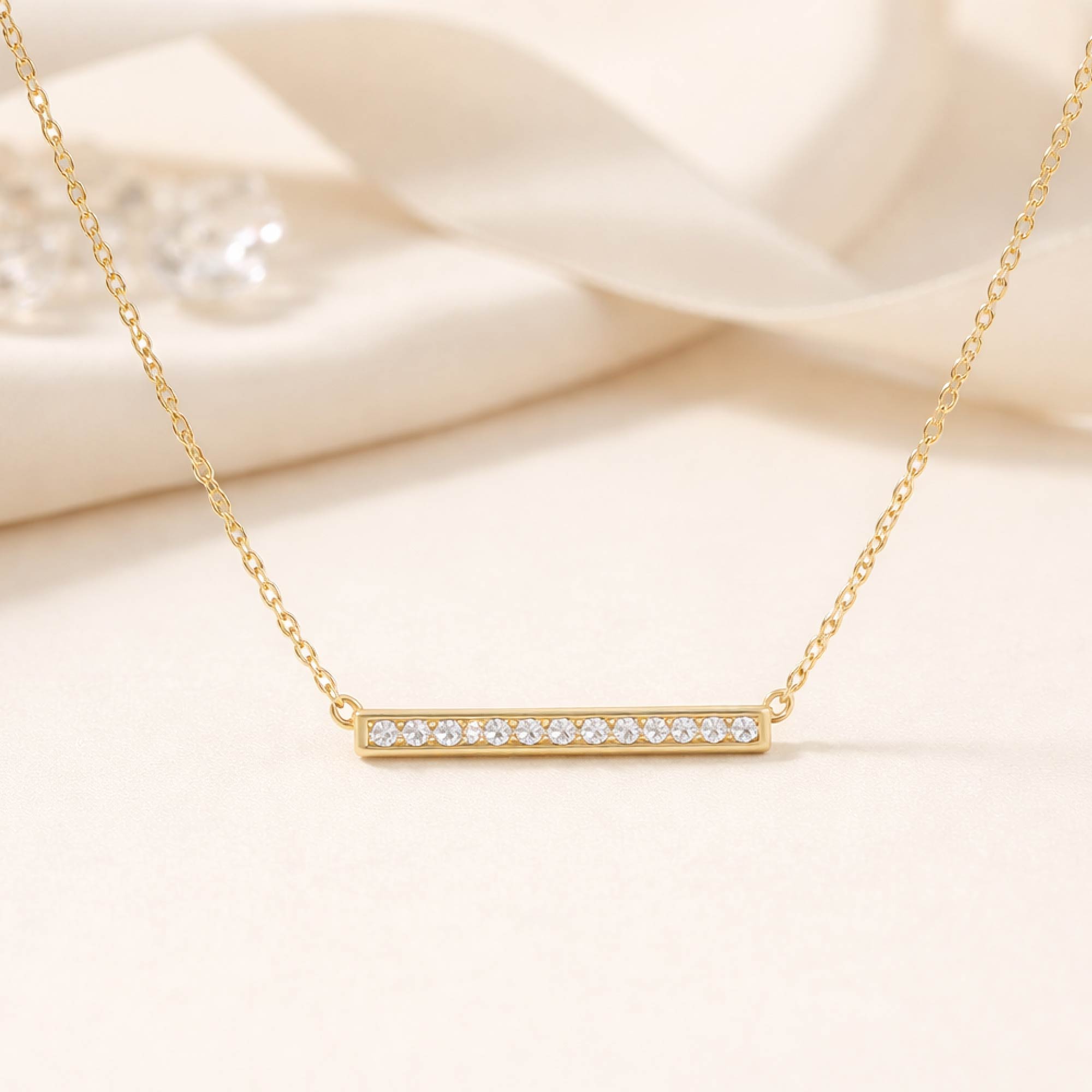 Gold necklace with a bar pendant on a soft beige background