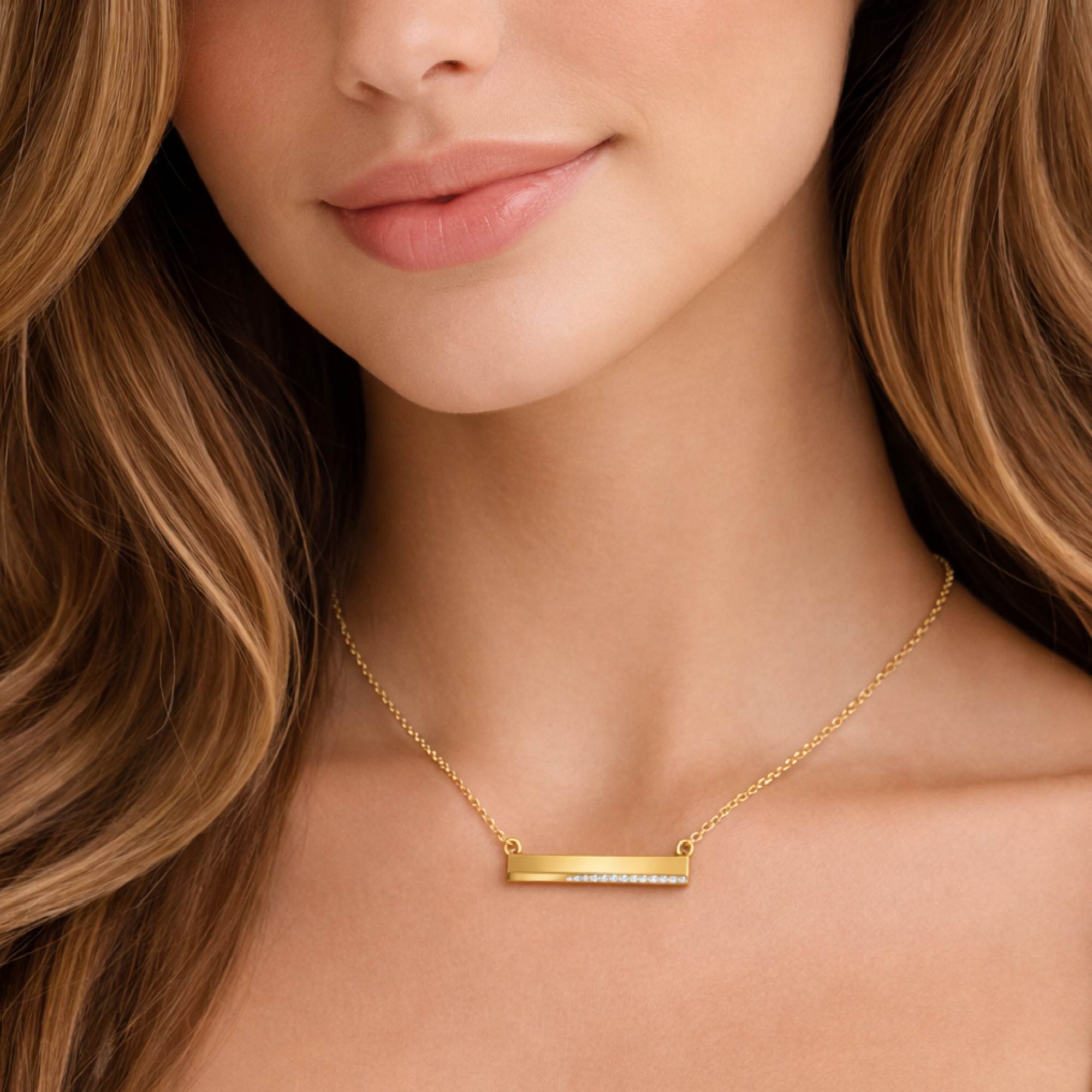 Close-up of a woman wearing a gold necklace with a bar pendant.