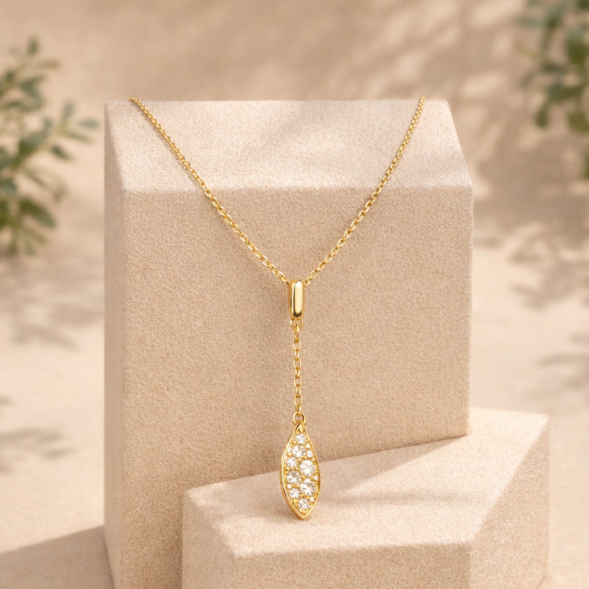 Gold necklace with a pendant on a beige stand with a natural background