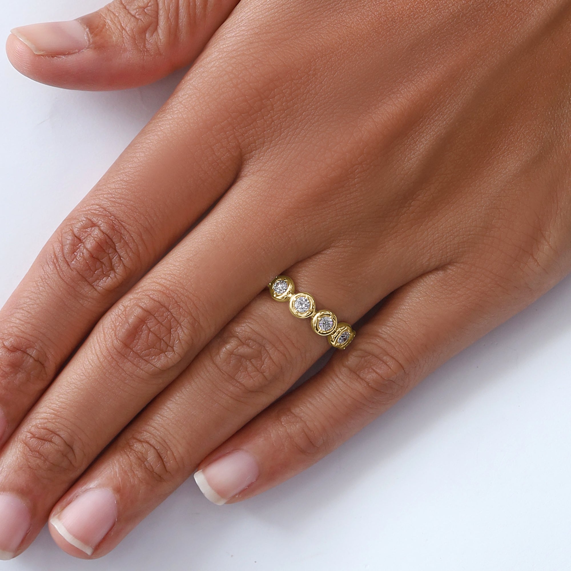 Gold ring with three diamonds on a hand against a white background