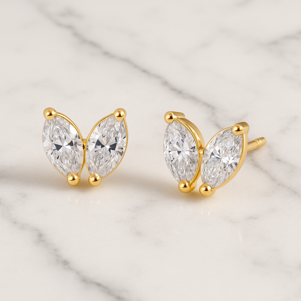 Gold earrings with clear gemstones on a marble surface
