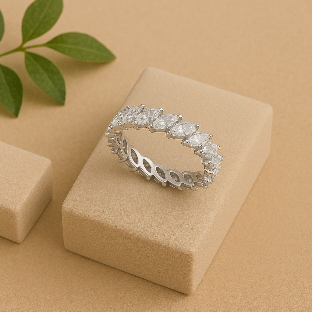 Silver ring with marquise-shaped diamonds on a beige box with green leaves in the background