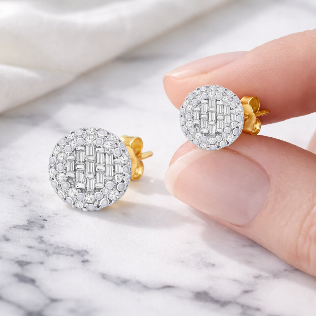 Gold and silver earrings held by a hand on a marble surface
