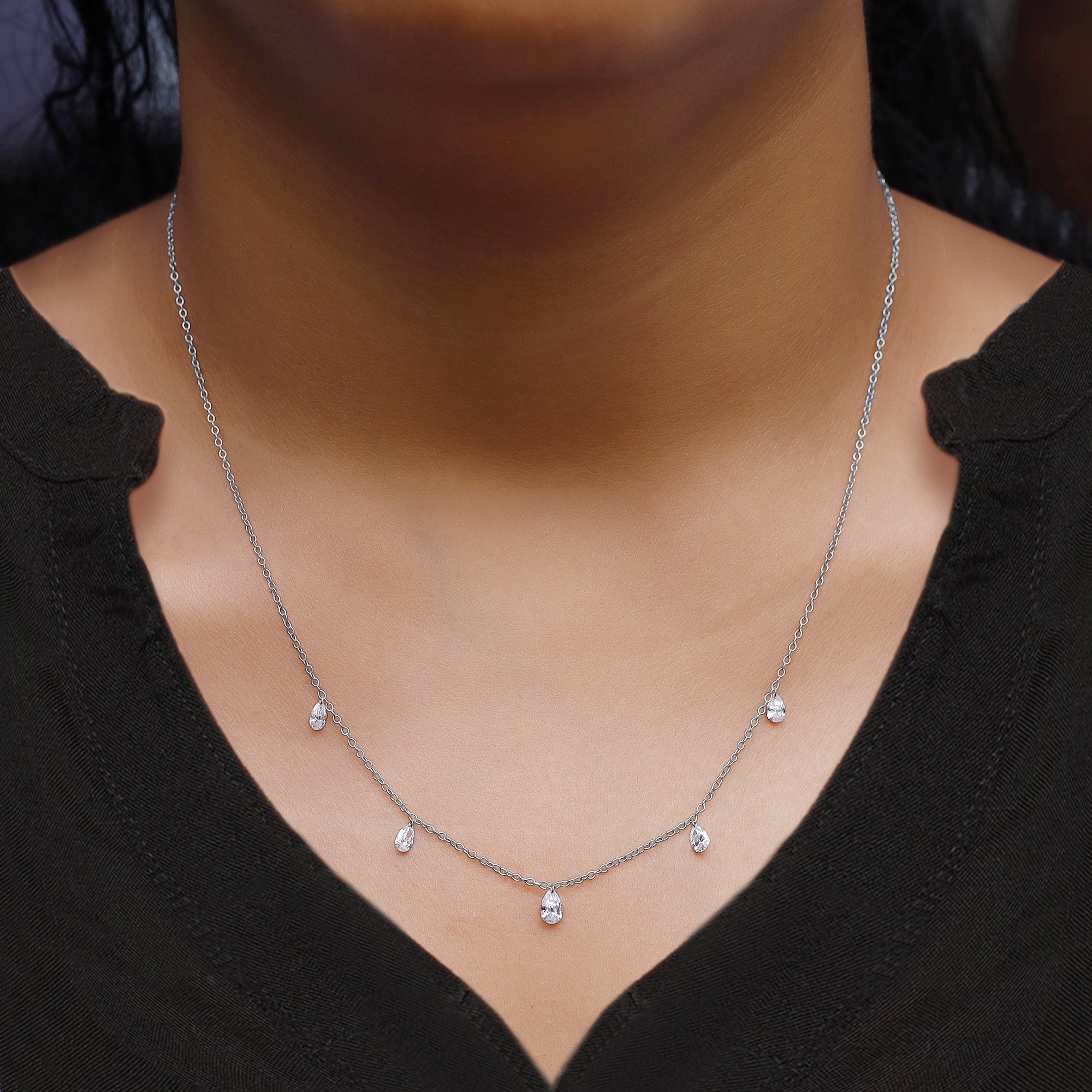 Necklace with small pendants on a person wearing a black top