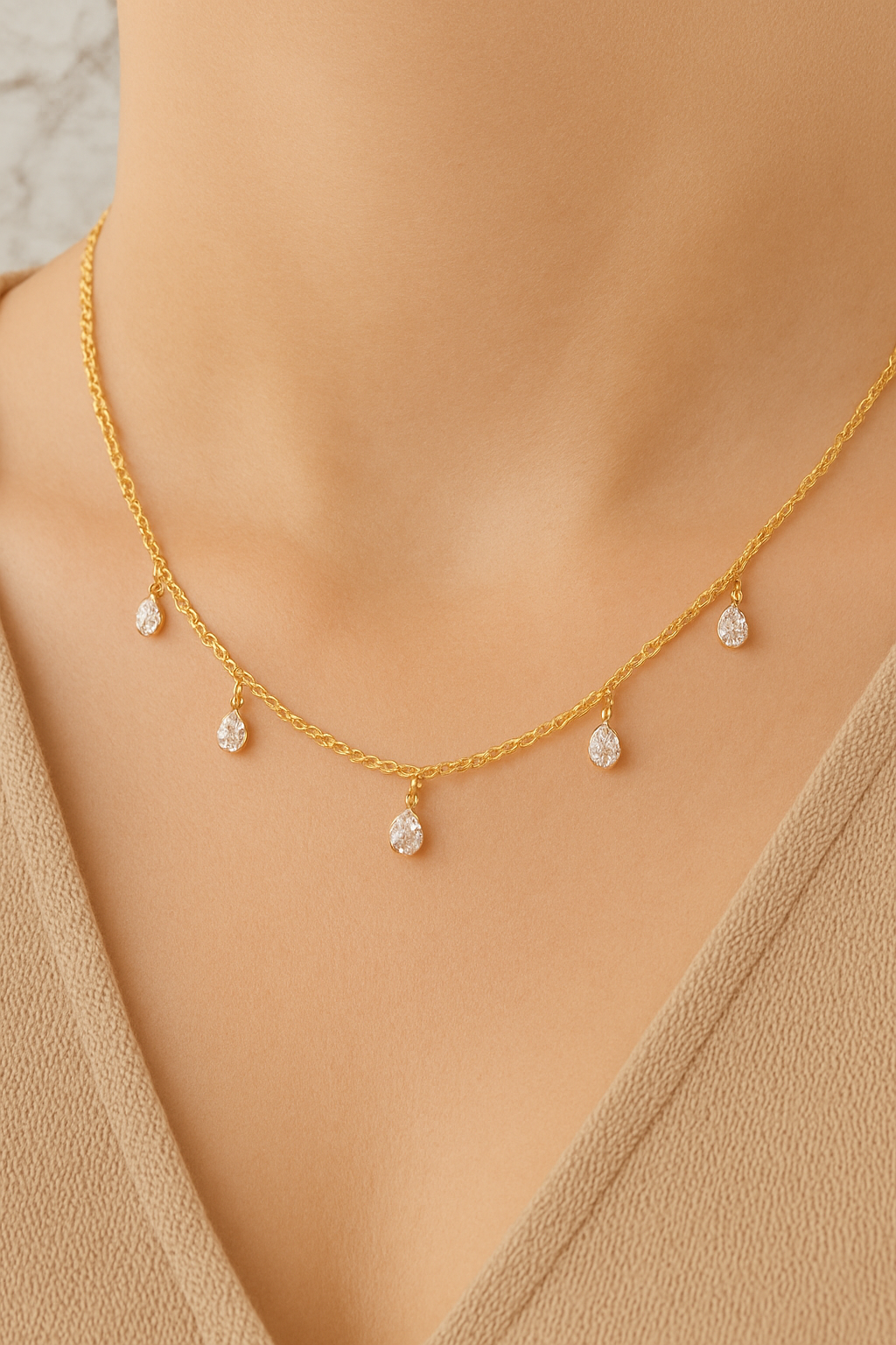 Gold necklace with small diamonds on a person wearing a beige top.