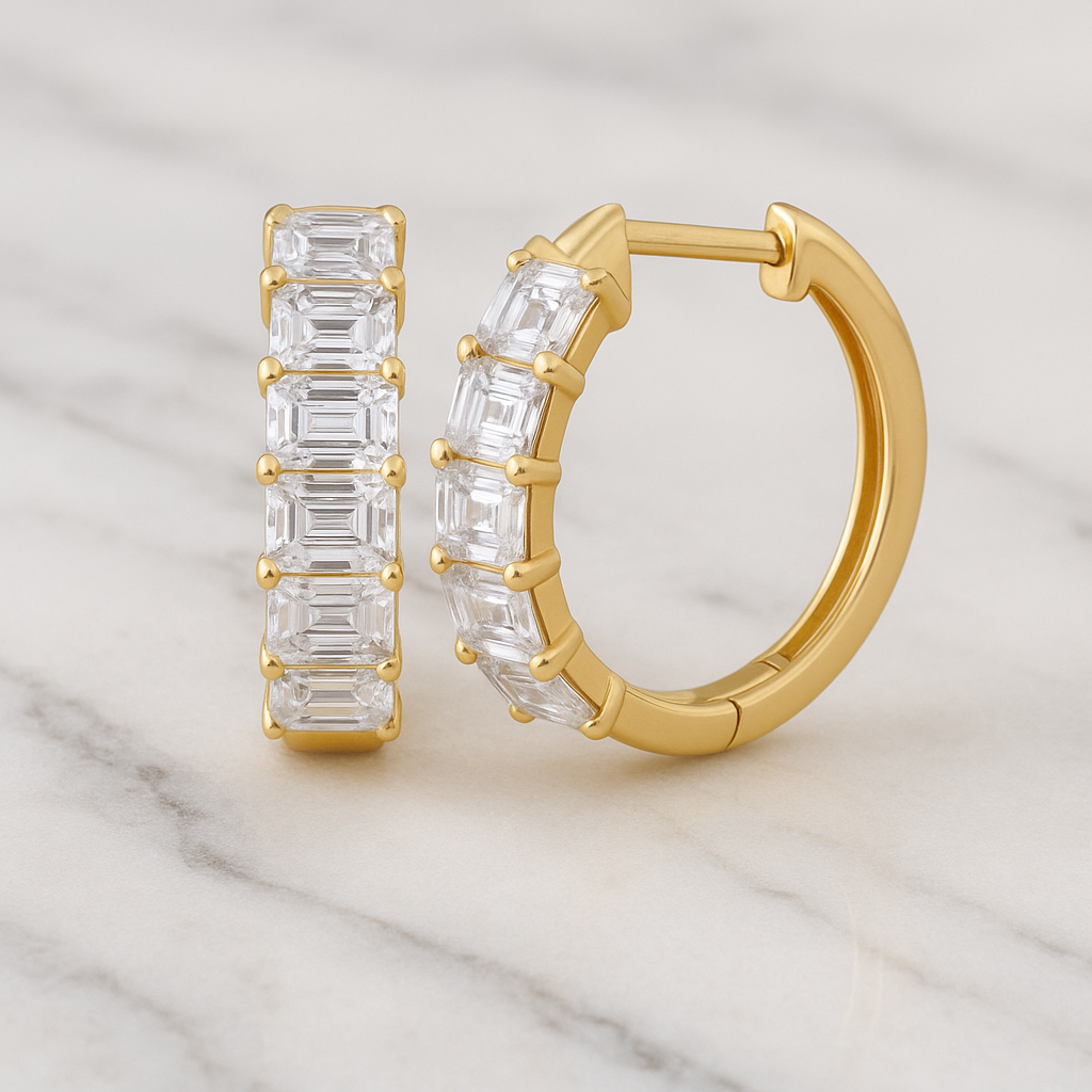 Gold hoop earrings with clear gemstones on a marble surface