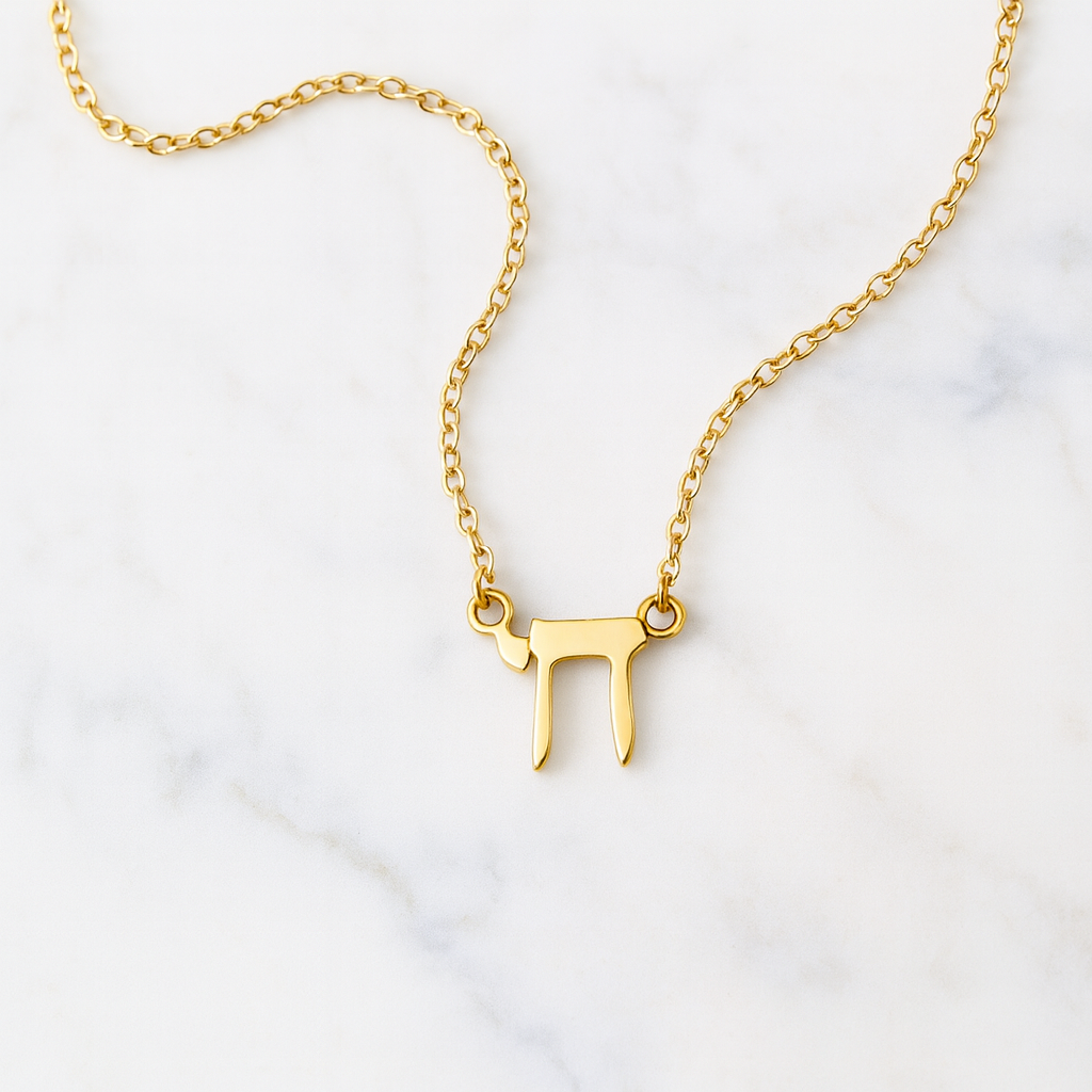 Gold necklace with a unique pendant on a white marble background