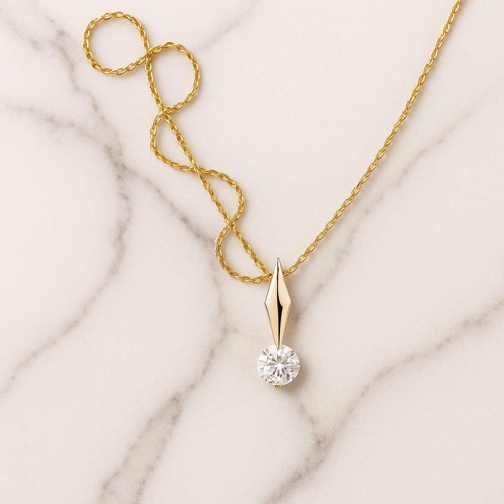 Gold necklace with a diamond pendant on a marble surface