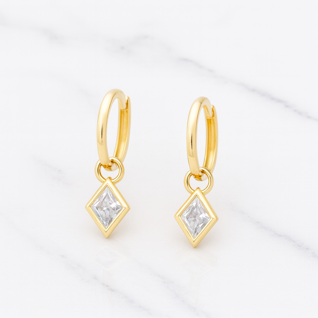 Gold hoop earrings with diamond-shaped pendants on a light background