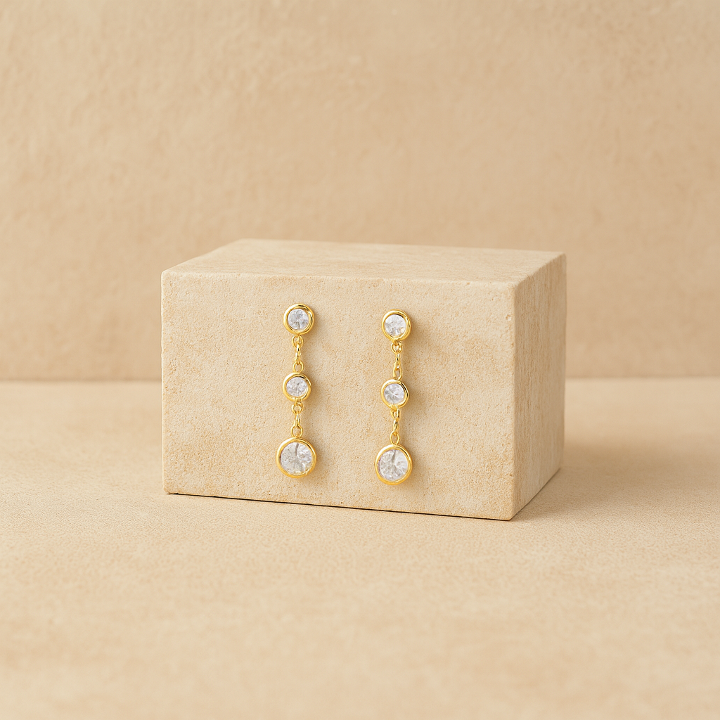 Gold earrings with clear stones on a beige jewelry box against a beige background