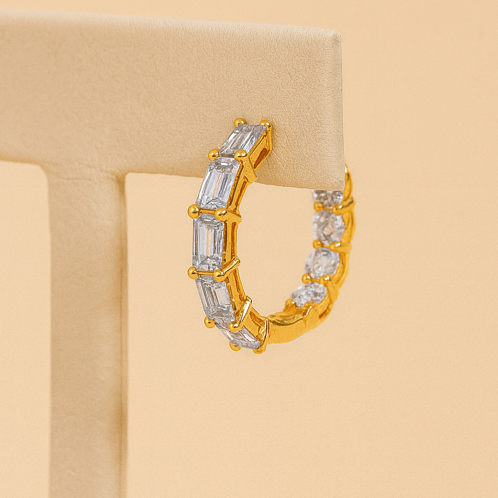 Gold hoop earring with clear stones on a beige background