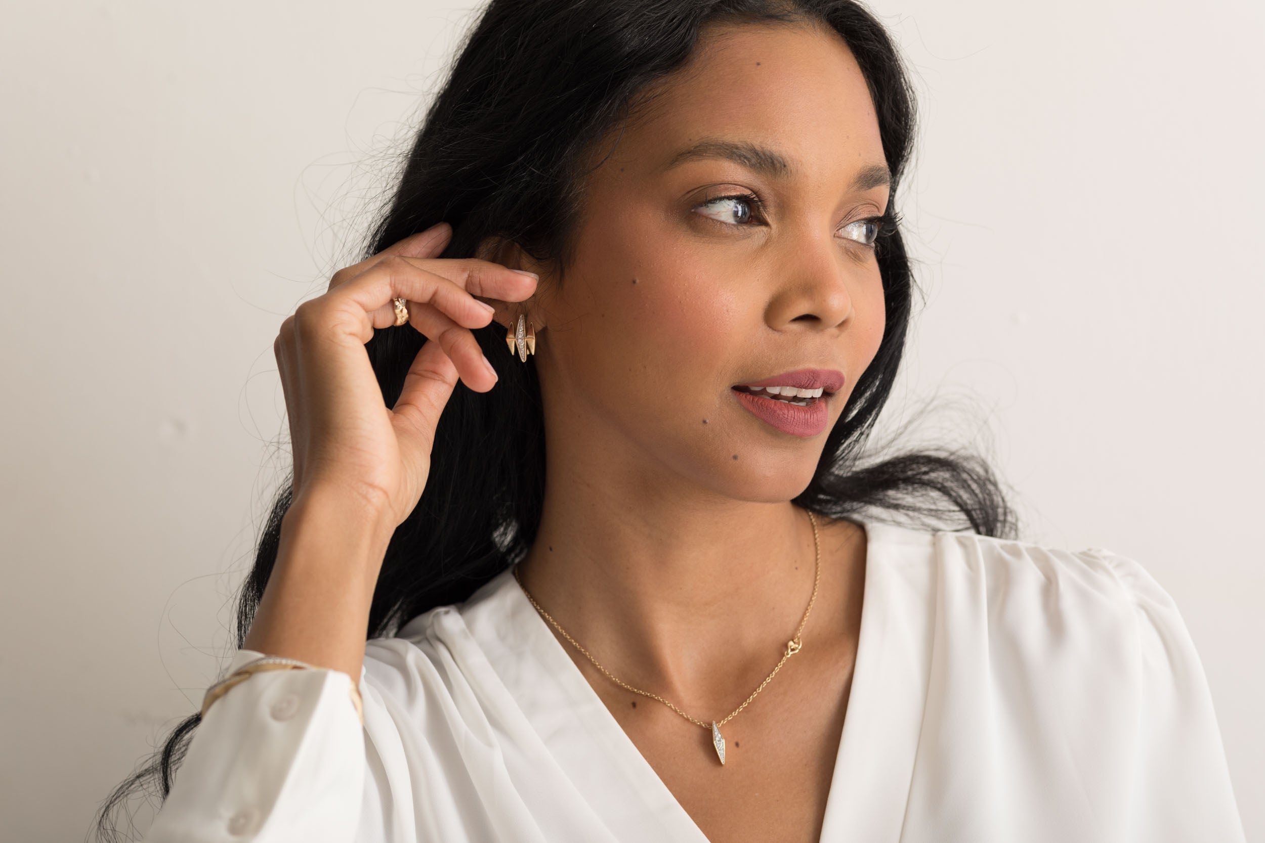 Model wearing 14K solid gold diamond earrings with a white blouse.