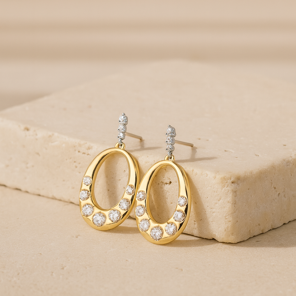 Gold hoop earrings with clear stones on a beige surface