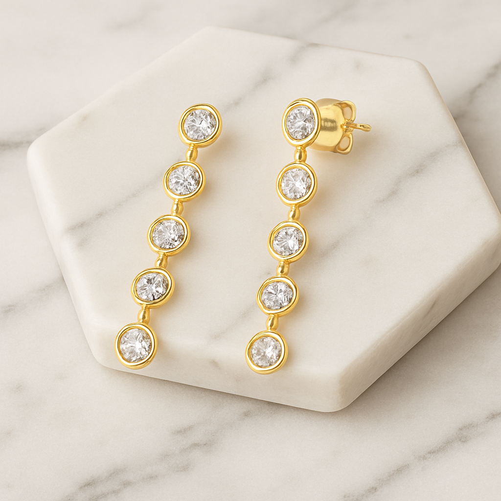 Gold earrings with clear gemstones on a marble surface