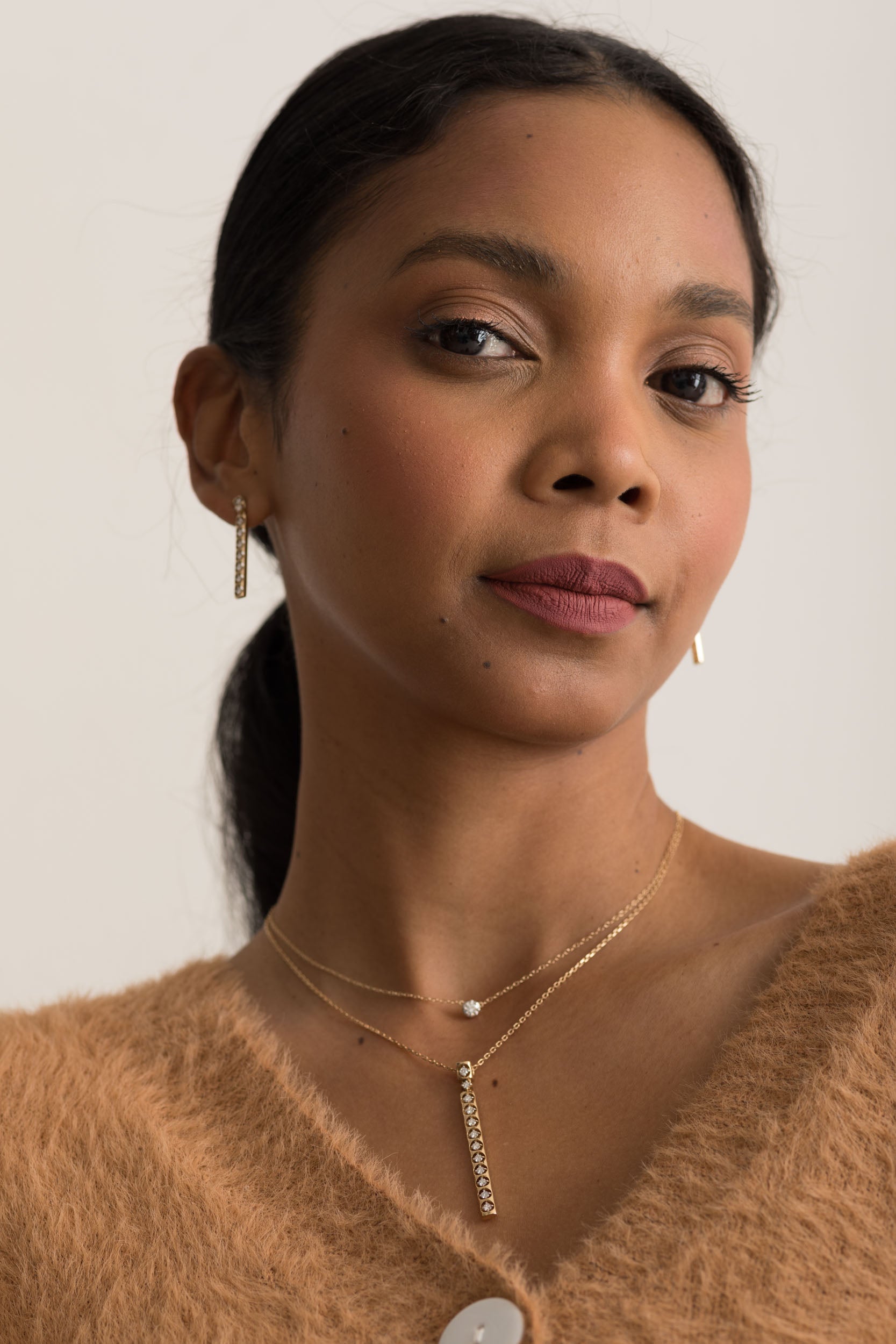 14K gold necklace with vertical diamond pendant on a woman's neck.