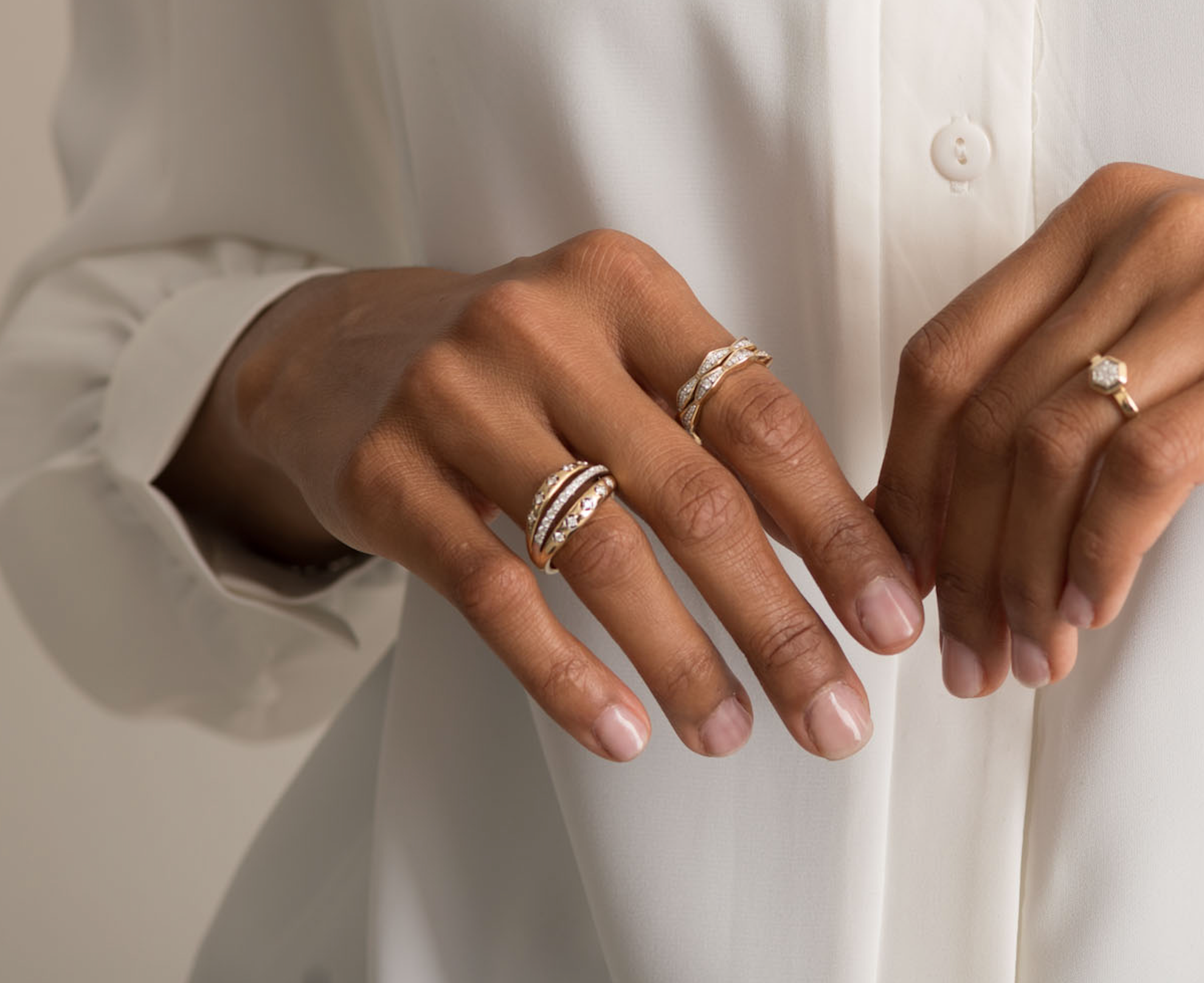 Close-up of hands wearing a 14K solid gold diamond ring with a white shirt background.