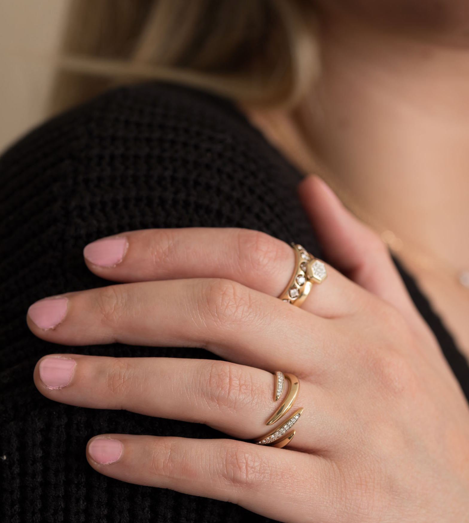 14K solid gold diamond ring on hand with pink nails and black sweater.