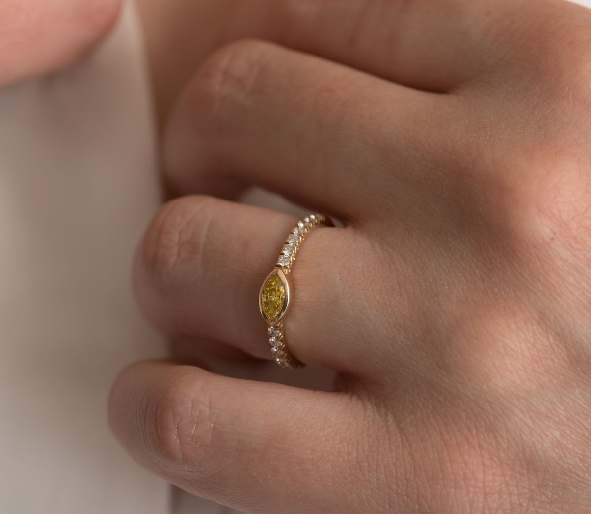 14K gold ring with a yellow diamond and small white diamonds on a hand.