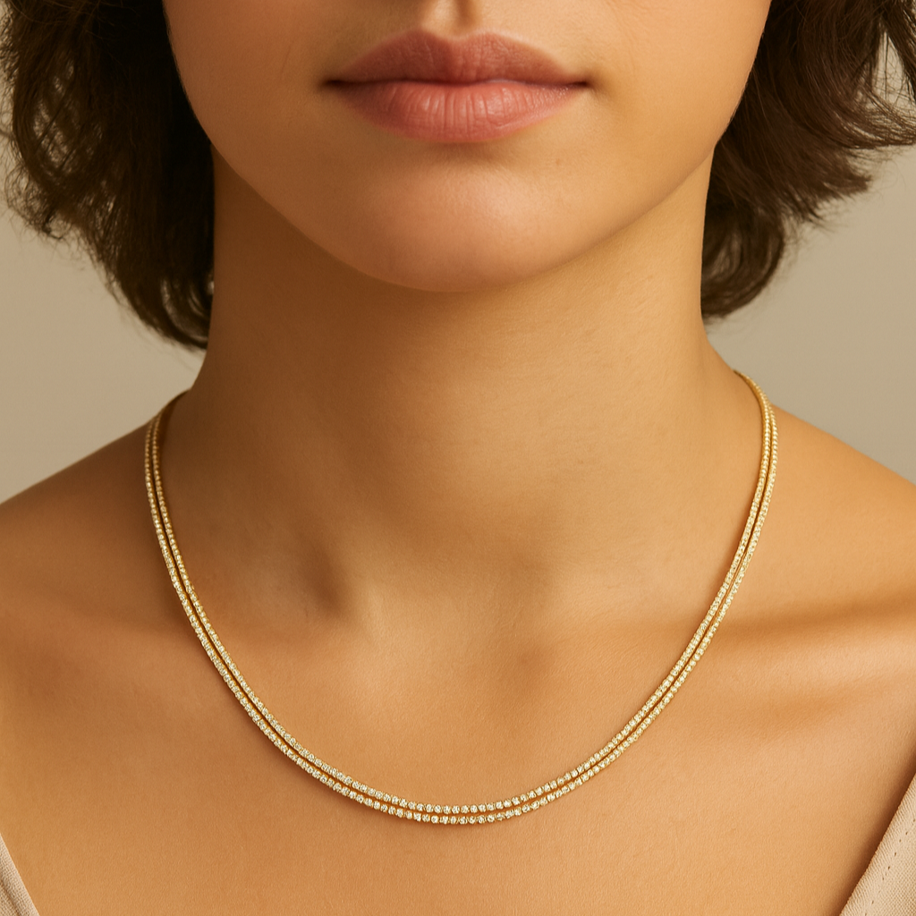 Close-up of a person wearing a gold necklace against a neutral background