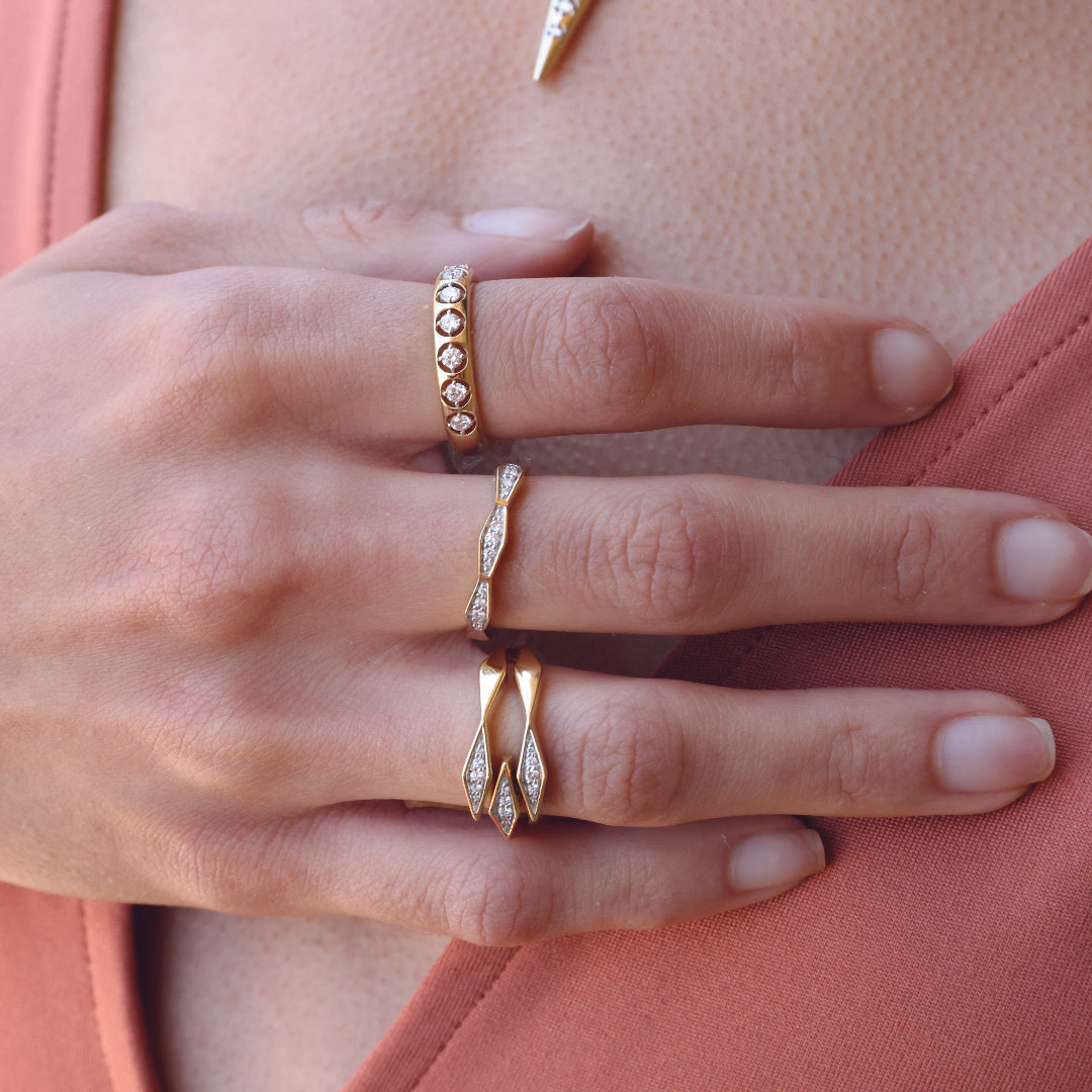 Close-up of hand wearing a 14K gold diamond triple bypass ring with intricate design.
