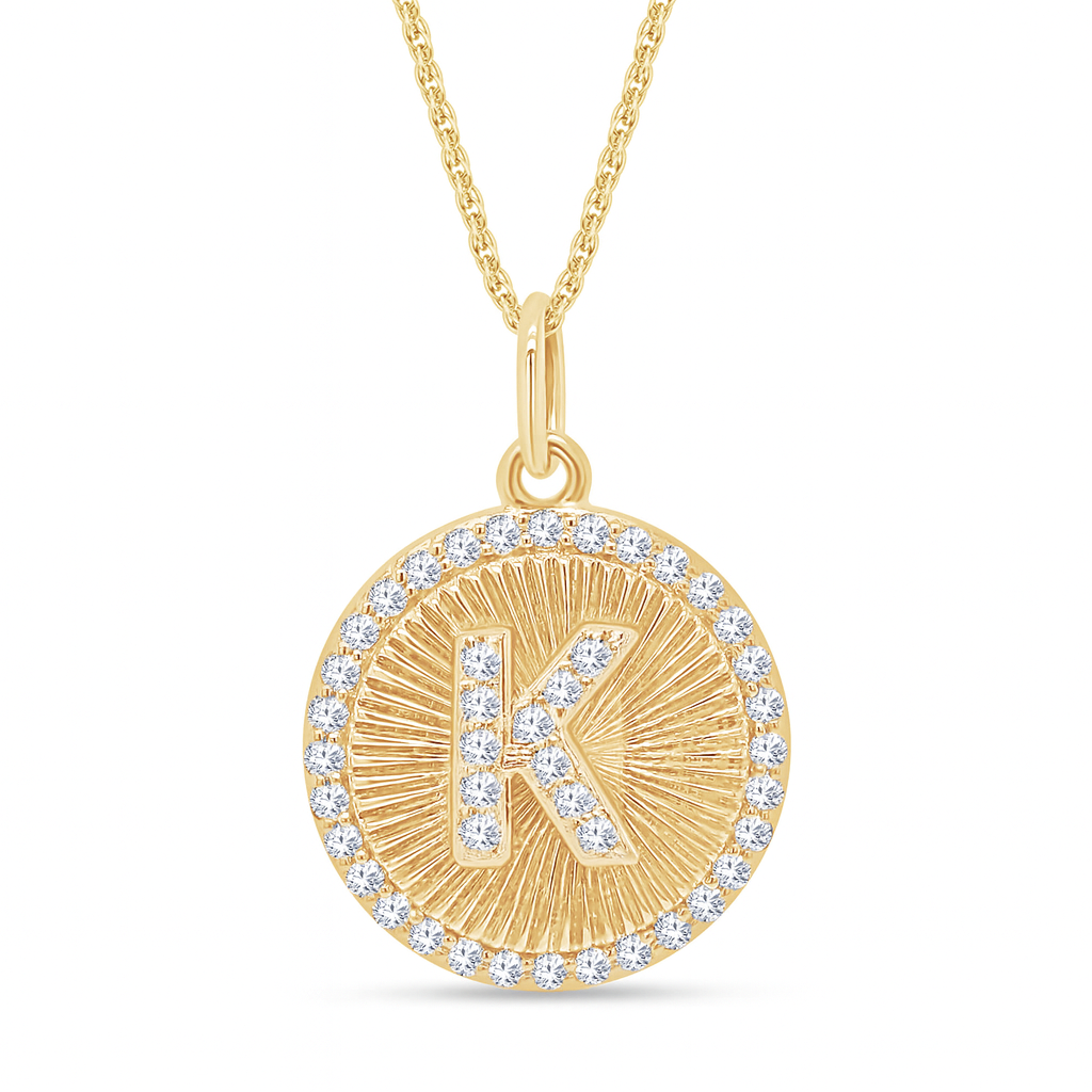 Gold necklace with a circular pendant featuring the letter 'K' and diamonds on a white background