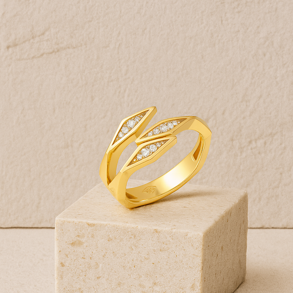 Gold leaf-shaped ring with embedded stones on a beige cube