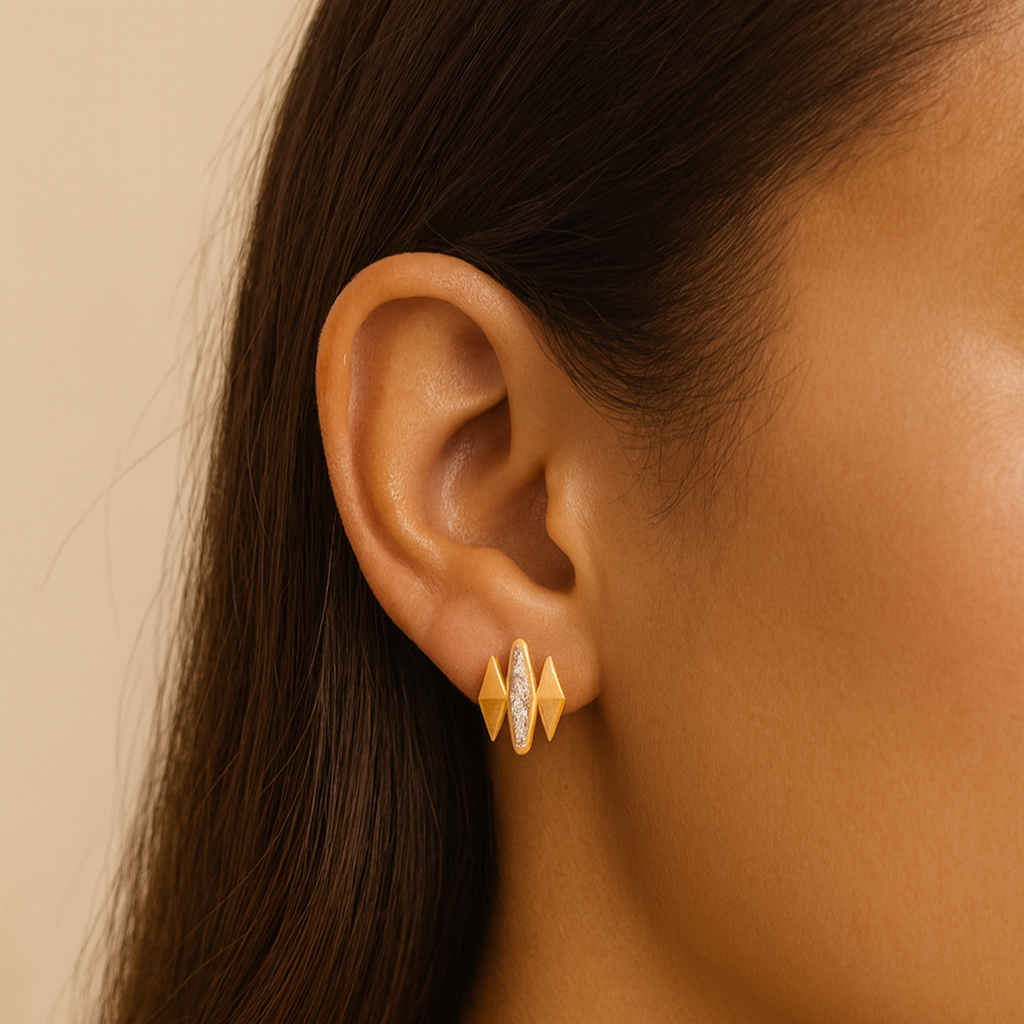 Close-up of a person wearing gold earrings with a neutral background