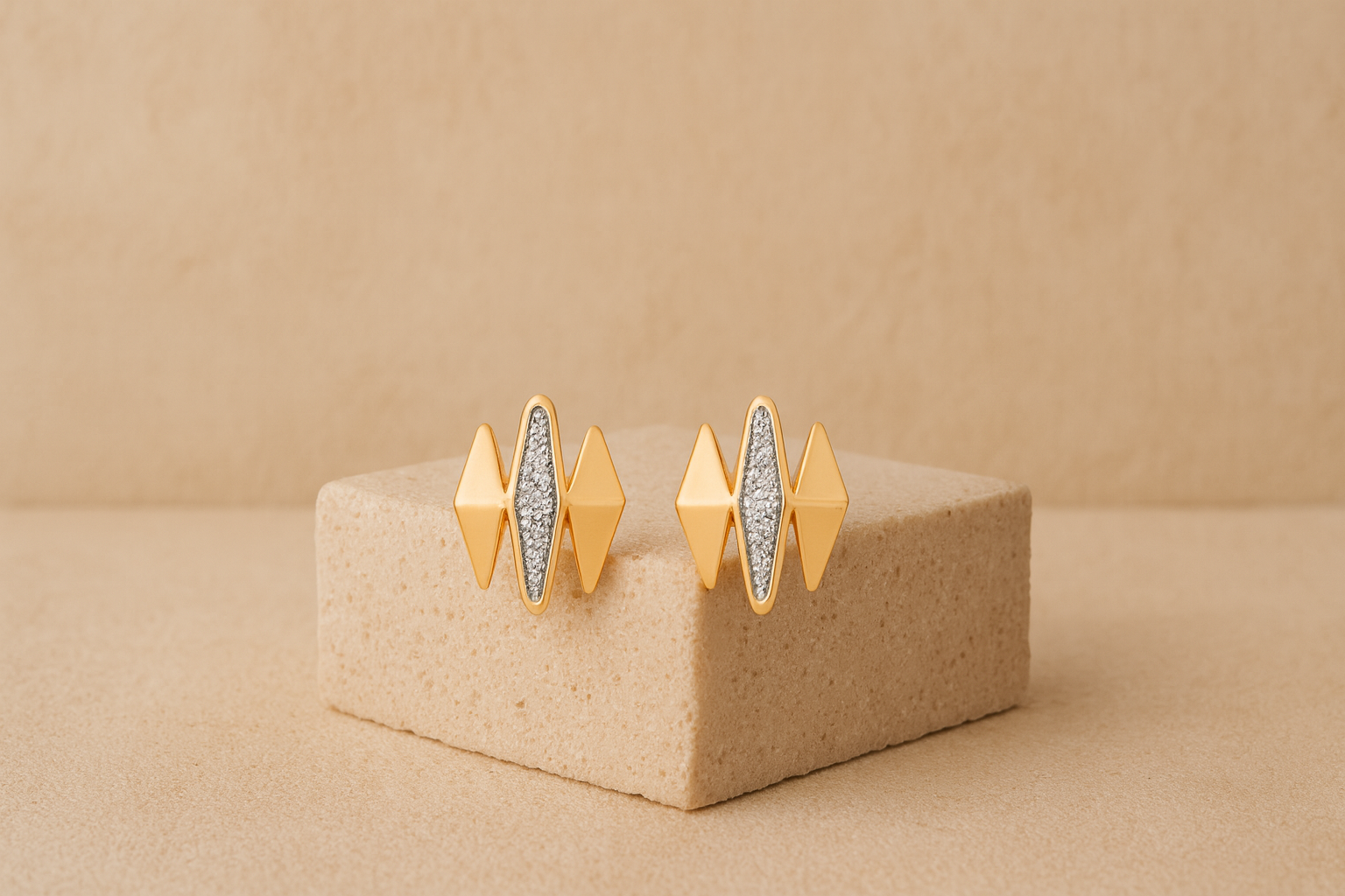Gold earrings with diamond-like stones on a beige stand against a beige background