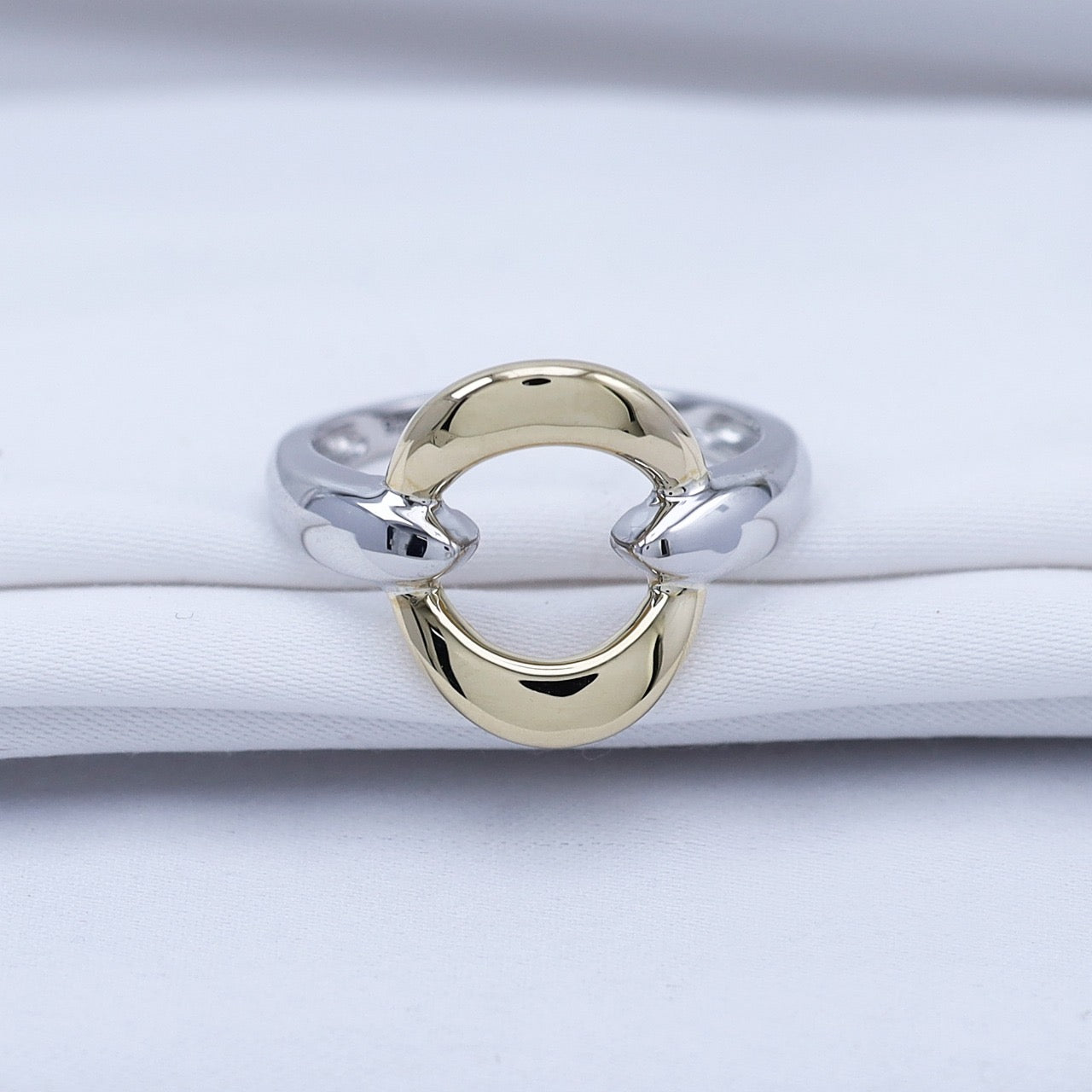 The Tova ring in 14K gold and sterling silver with a modern circular design on white fabric.