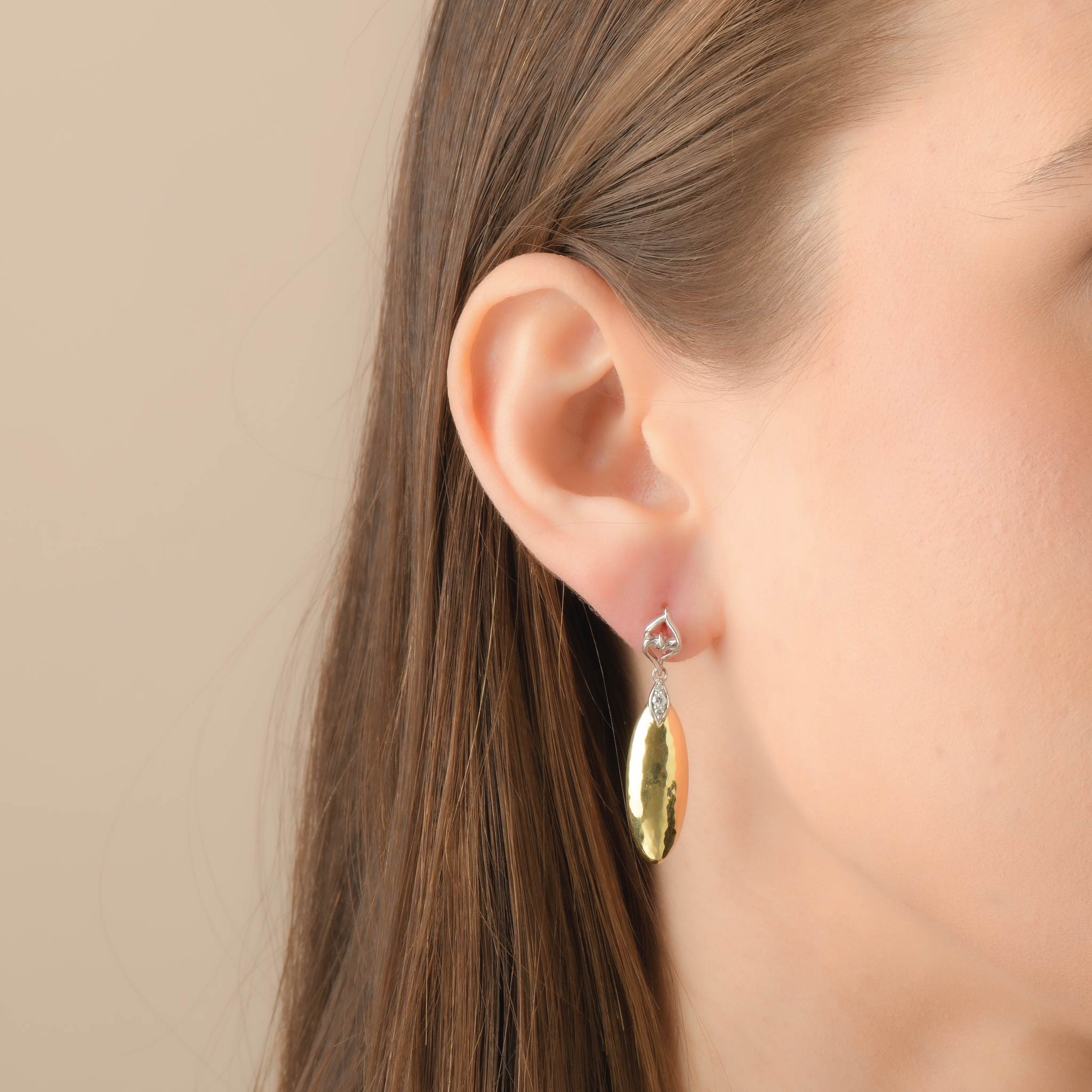 Gold teardrop earrings with gemstone on woman's ear, sterling silver and 14K gold.