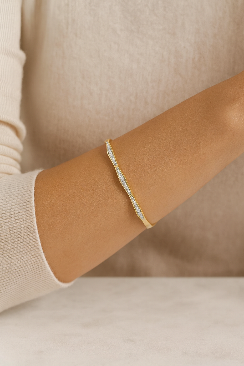 Gold bracelet on a person's wrist with a neutral background