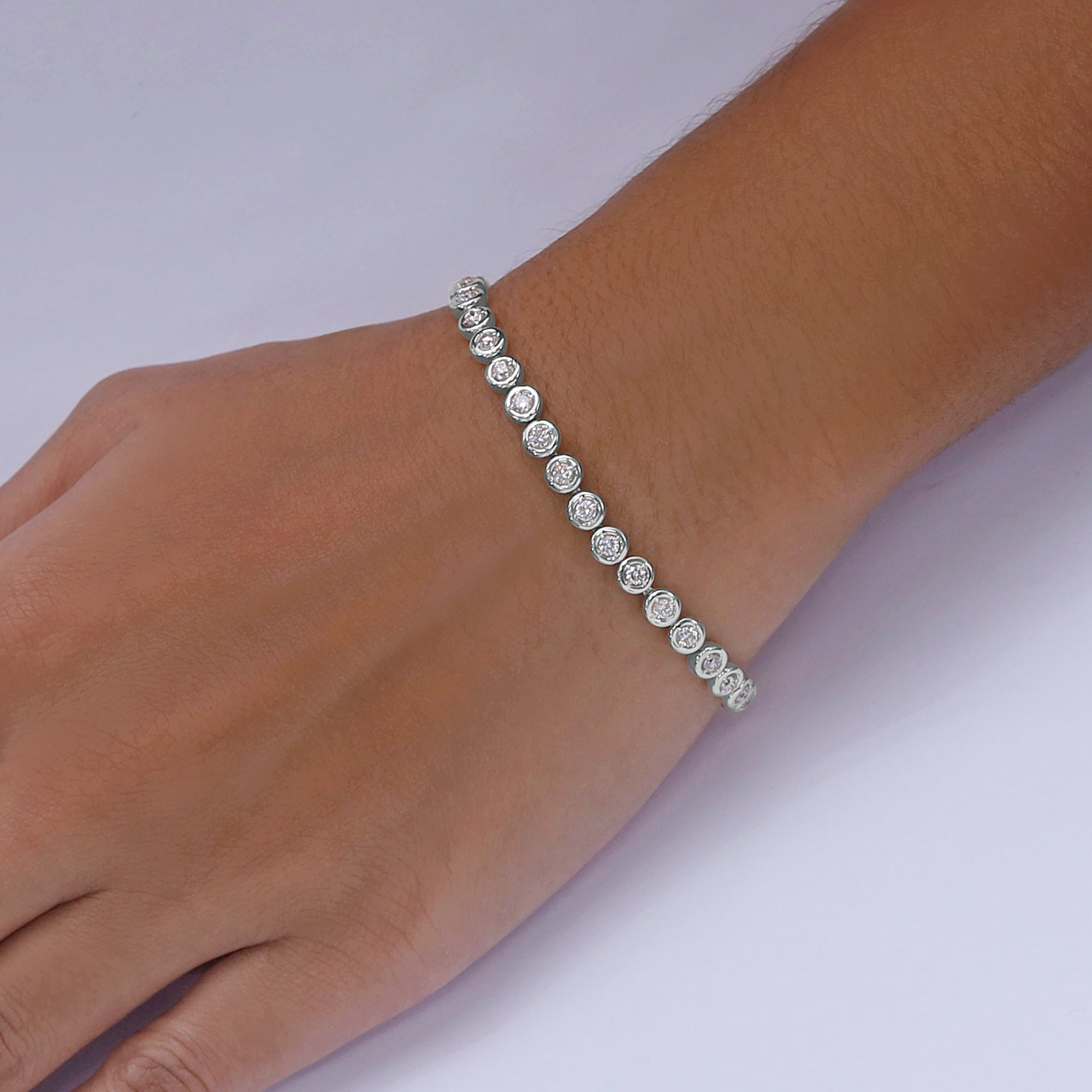 Silver bracelet with clear stones on a wrist against a white background