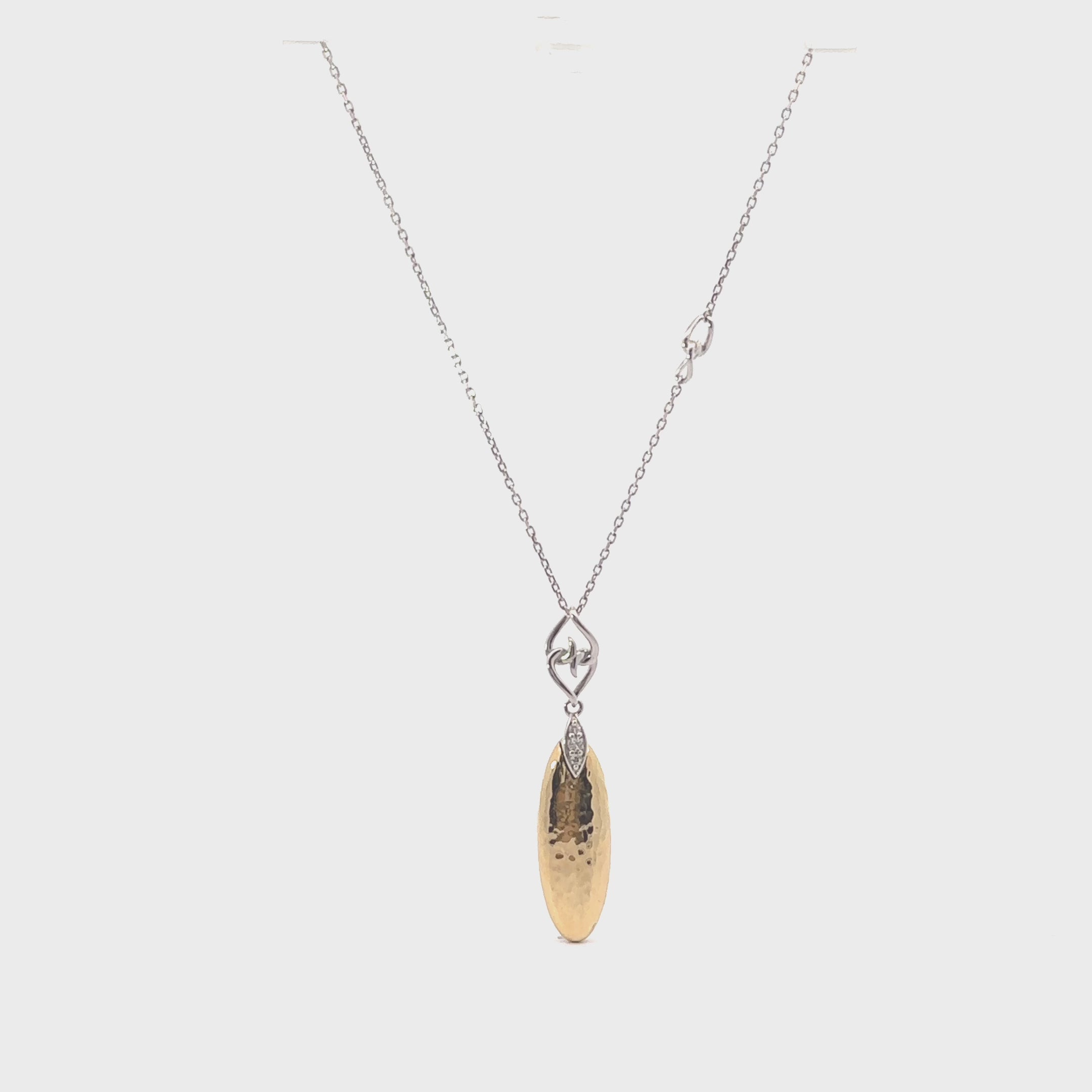 Hammered gold and silver teardrop pendant necklace on white textured surface with flowers.