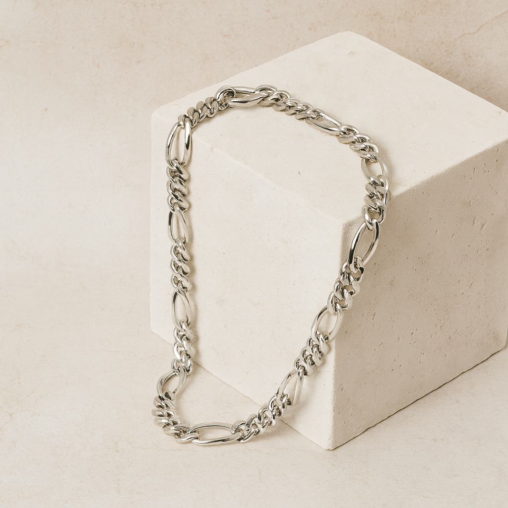 Silver chain necklace on a beige block with a neutral background
