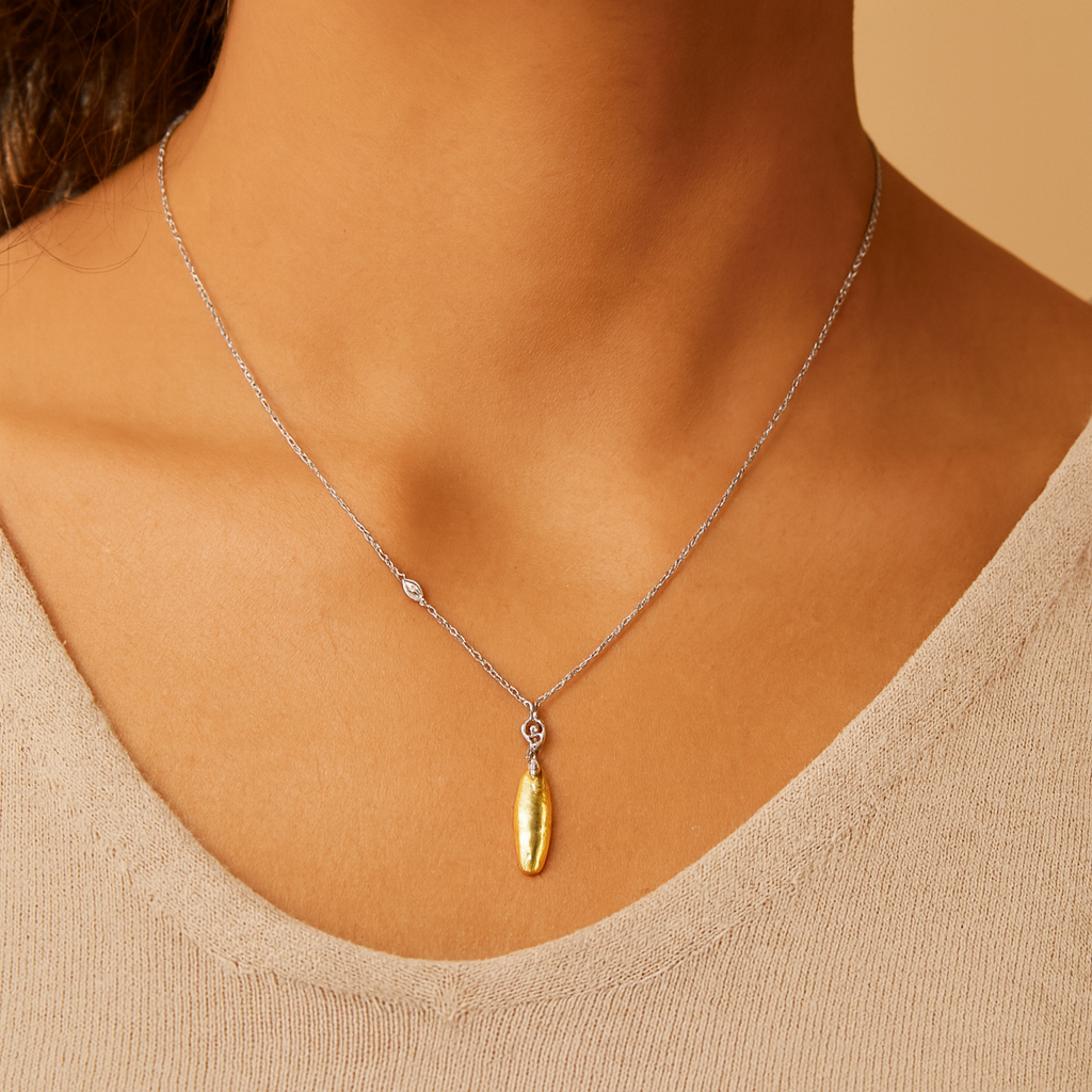 Necklace with a gold pendant worn by a person against a neutral background