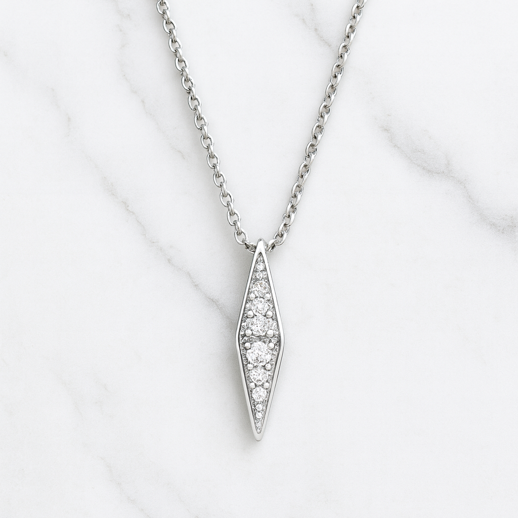 Silver necklace with a diamond pendant on a white marble surface