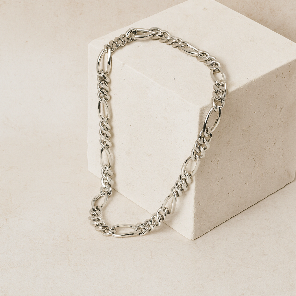 Silver chain necklace on a beige block with a neutral background