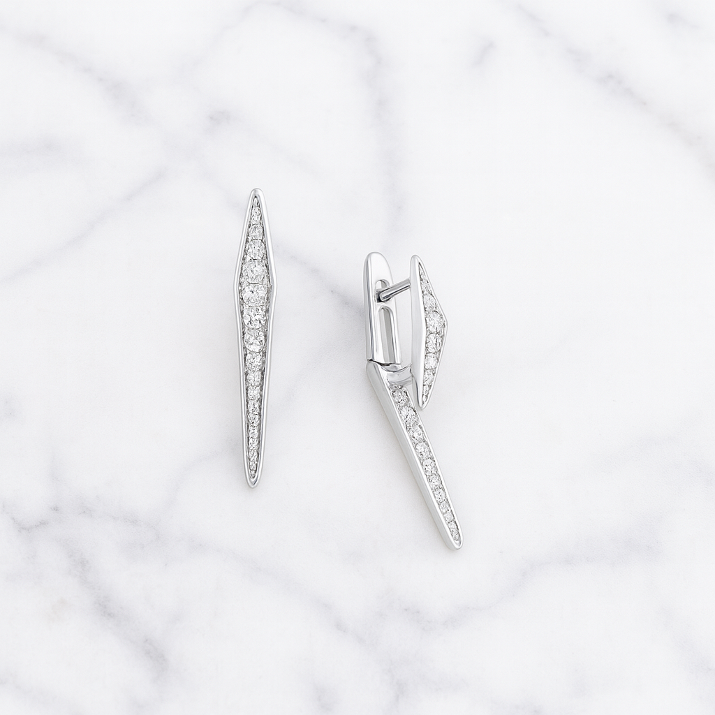 Pair of silver earrings with diamond accents on a marble background